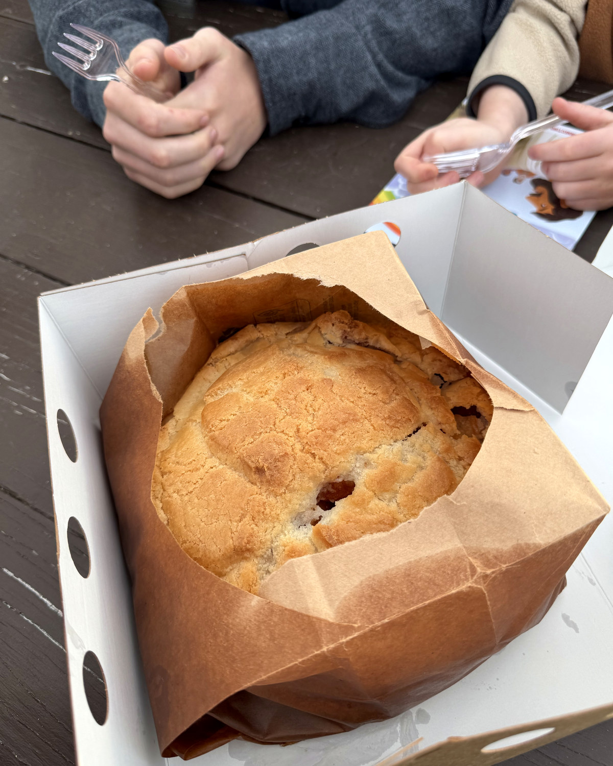 The Elegant Farmer apple pie, baked in a paper bag, open in its box with two forks ready