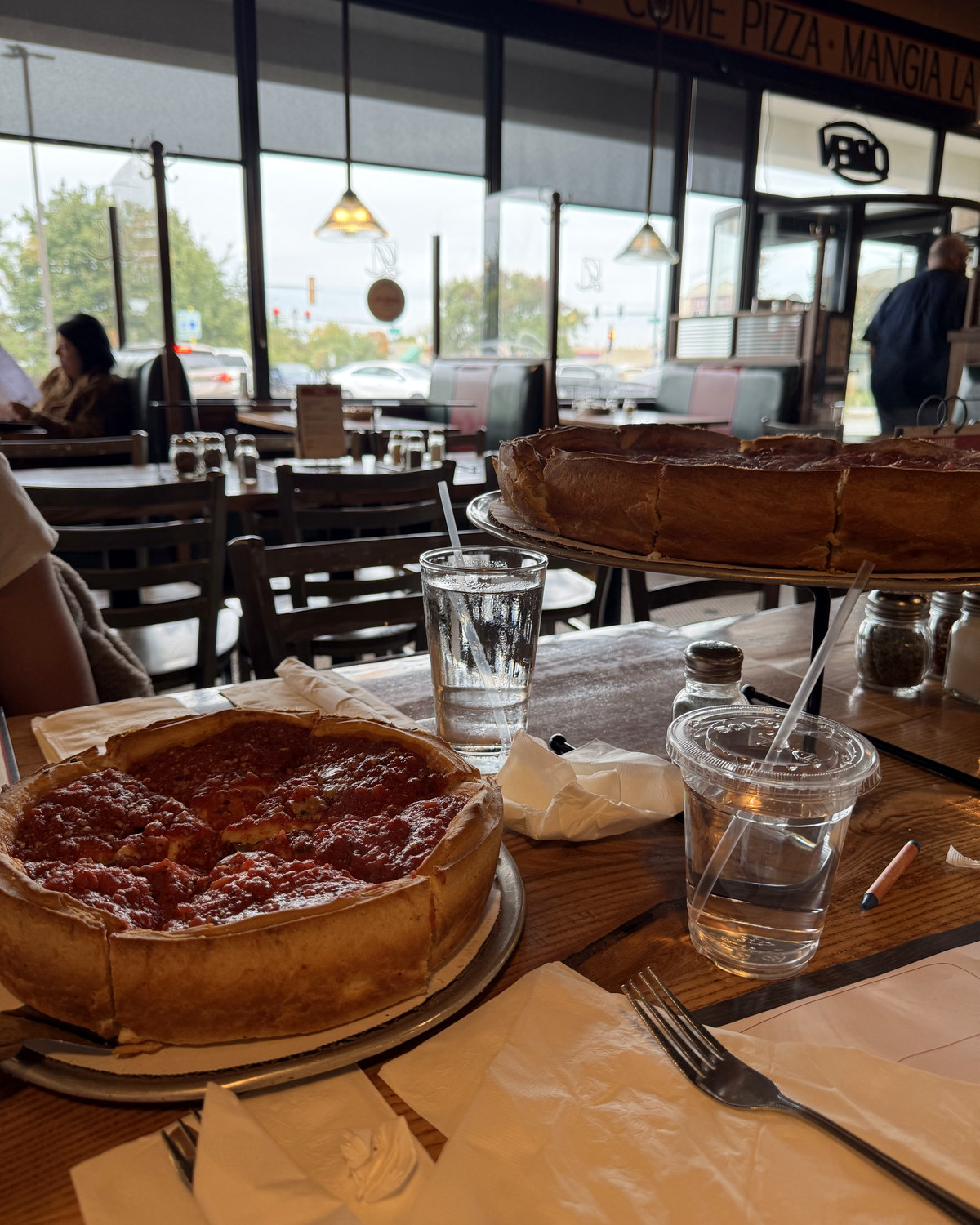 Two Giordano's deep dish pizzas on the table, one stacked on a rack