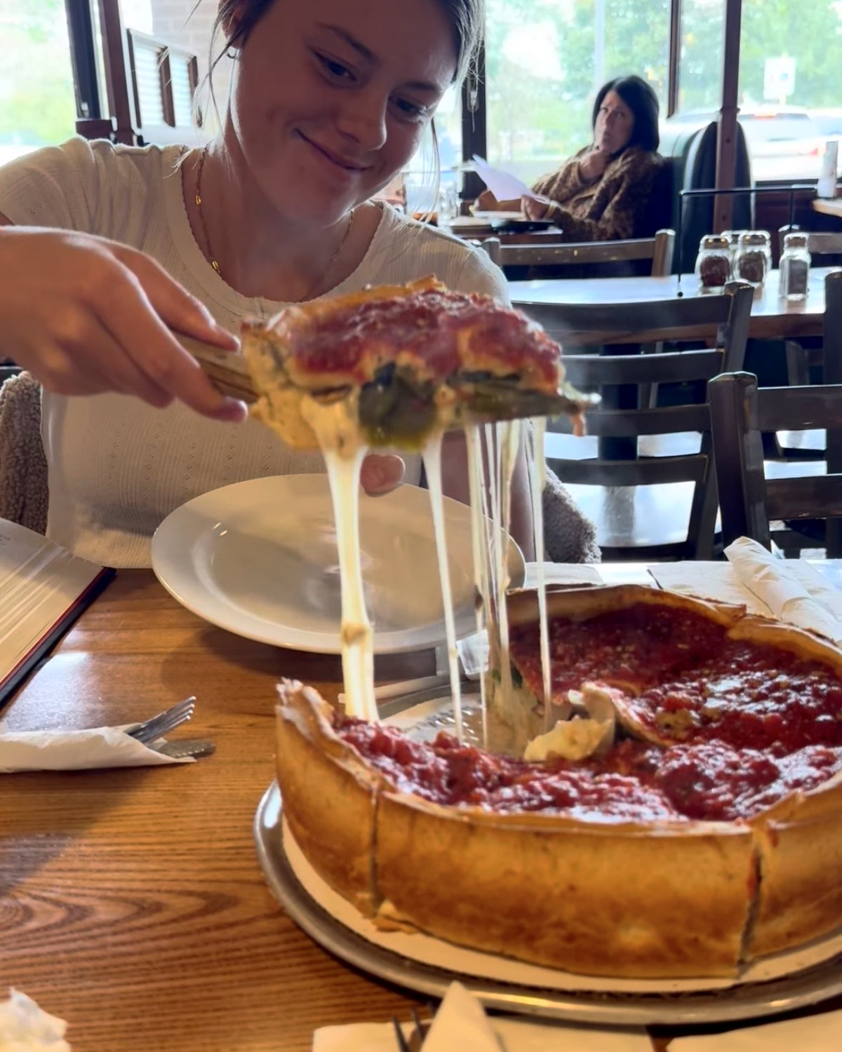One of the girls lifting a slice of deep dish with a foot of cheese stretching off it