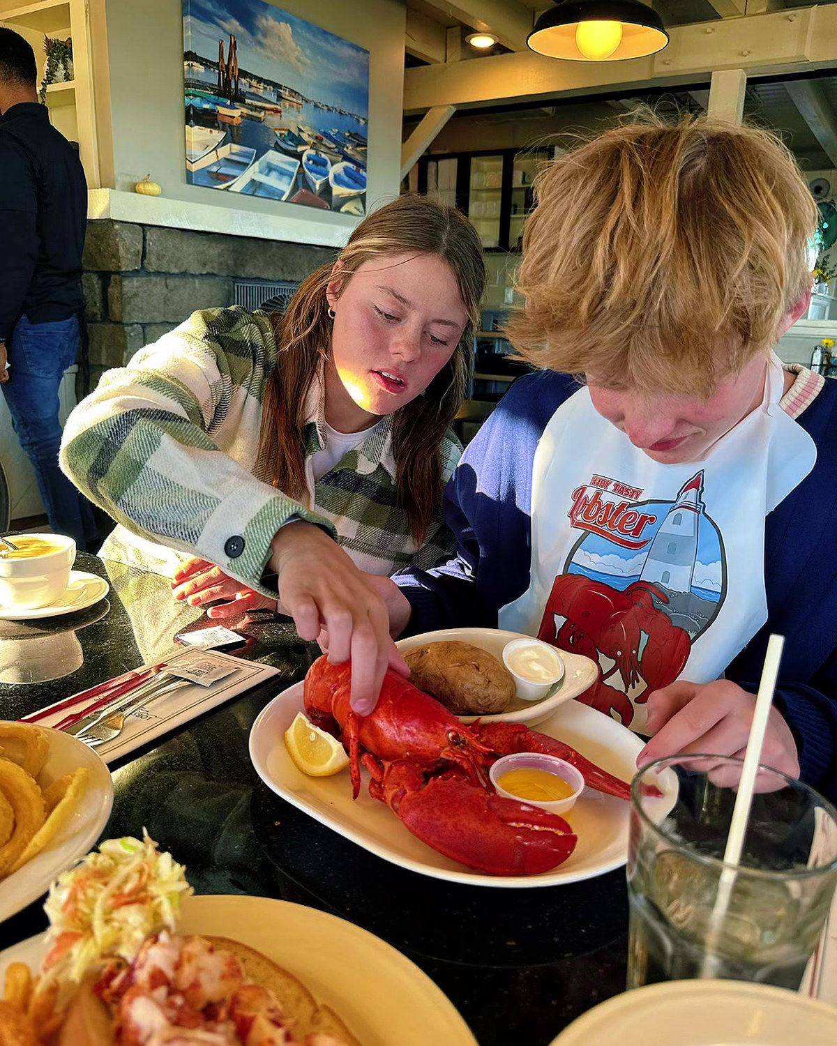 Two of the kids working on a whole lobster at a table in Perkins Cove