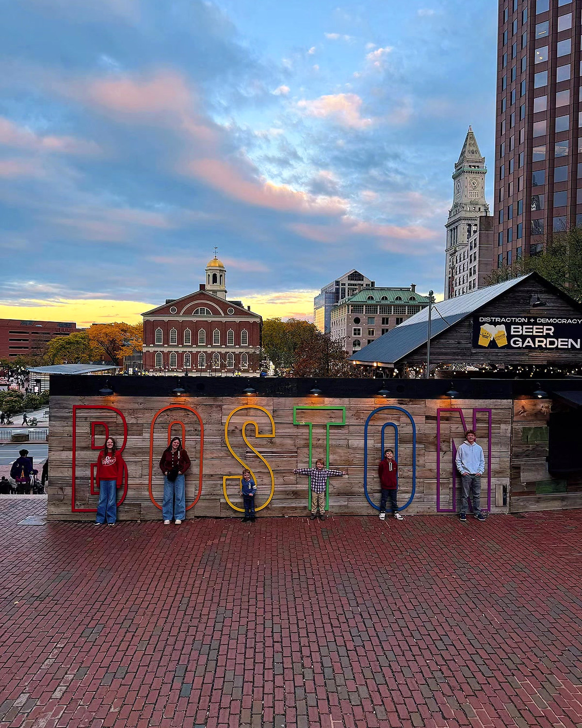 The kids standing in the letters of the big BOSTON sign at Faneuil Hall at dusk