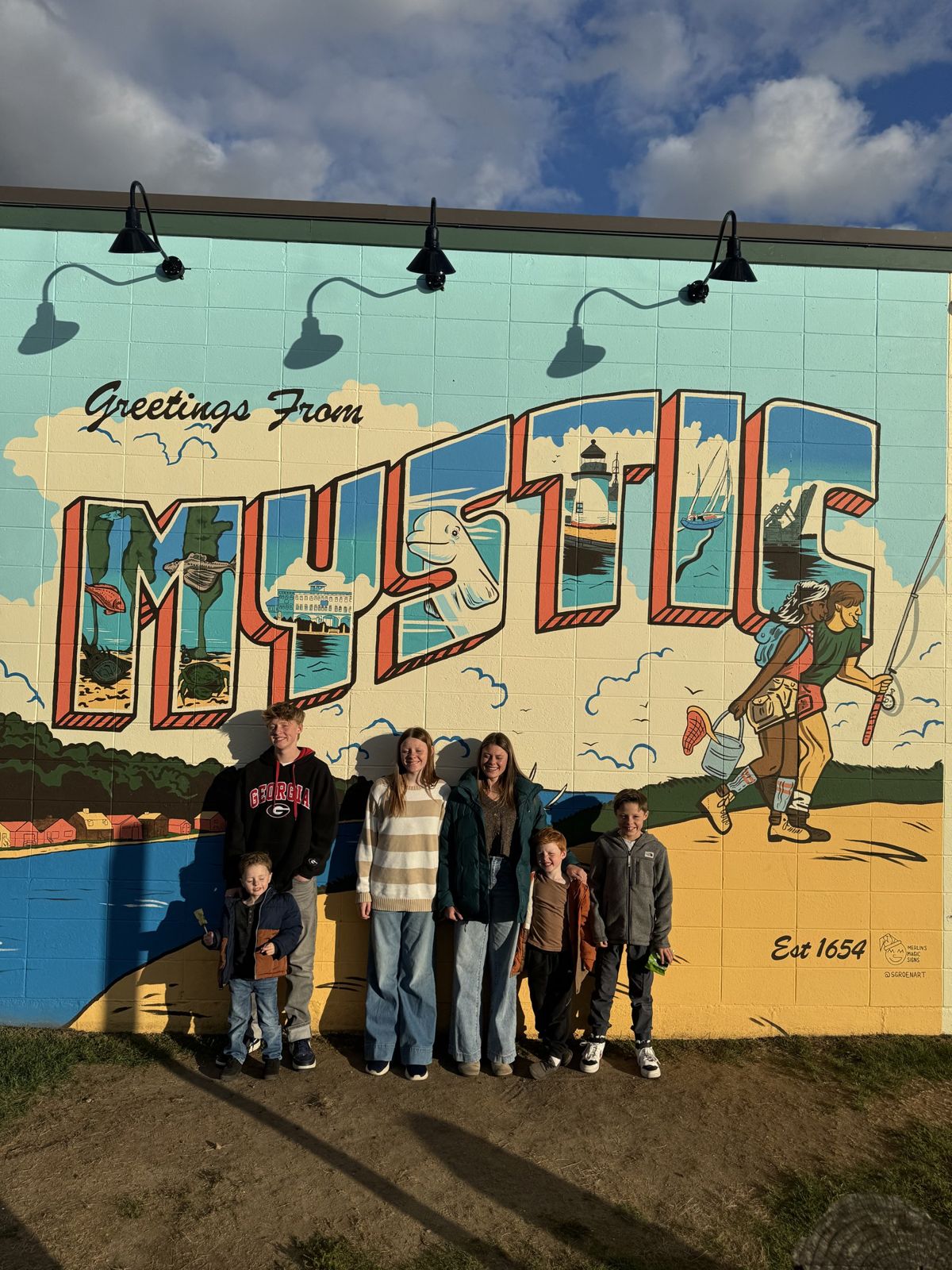 Our family in front of the Greetings from Mystic mural