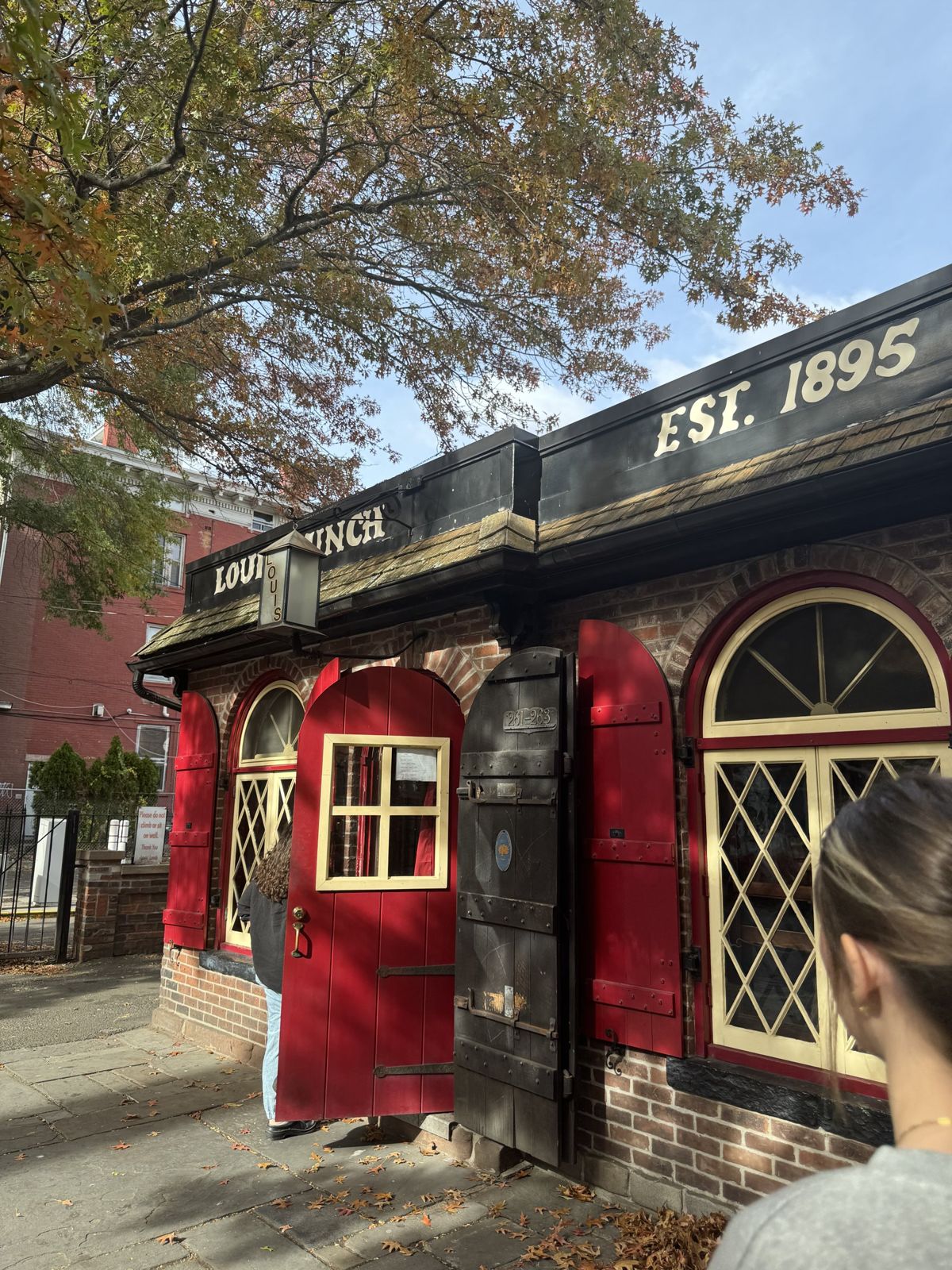 The red front of Louis' Lunch in New Haven with fall leaves