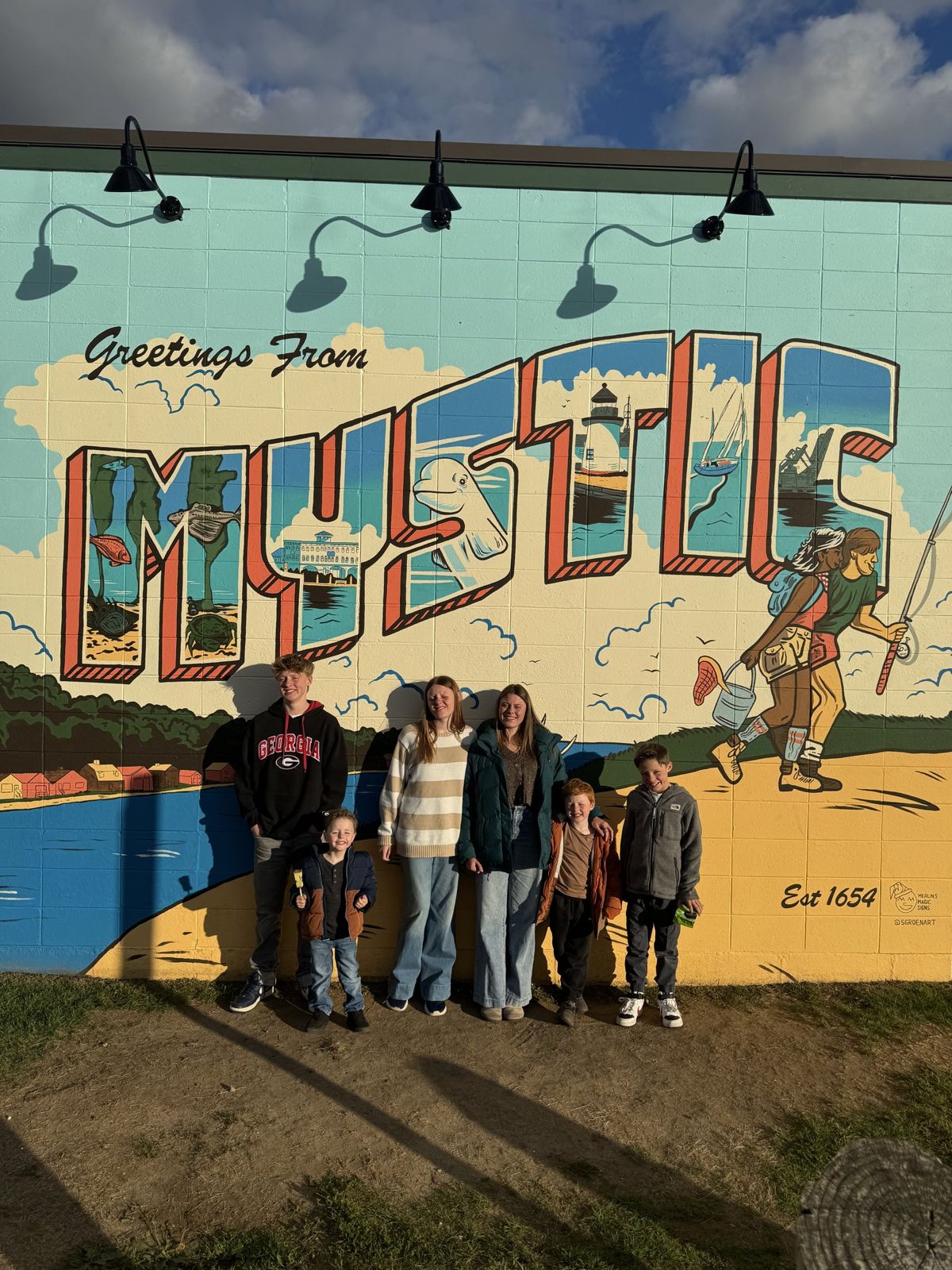 Our family in front of the Greetings from Mystic mural
