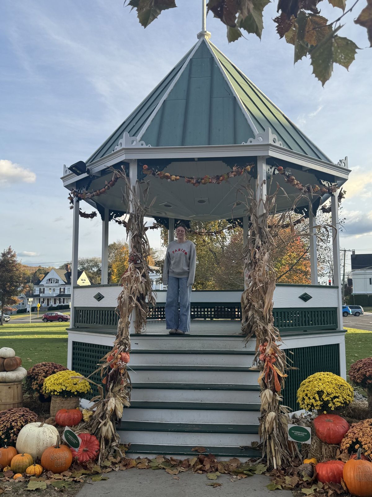 The bandstand on the New Milford green decorated with corn stalks, mums and pumpkins, with my daughter on the steps