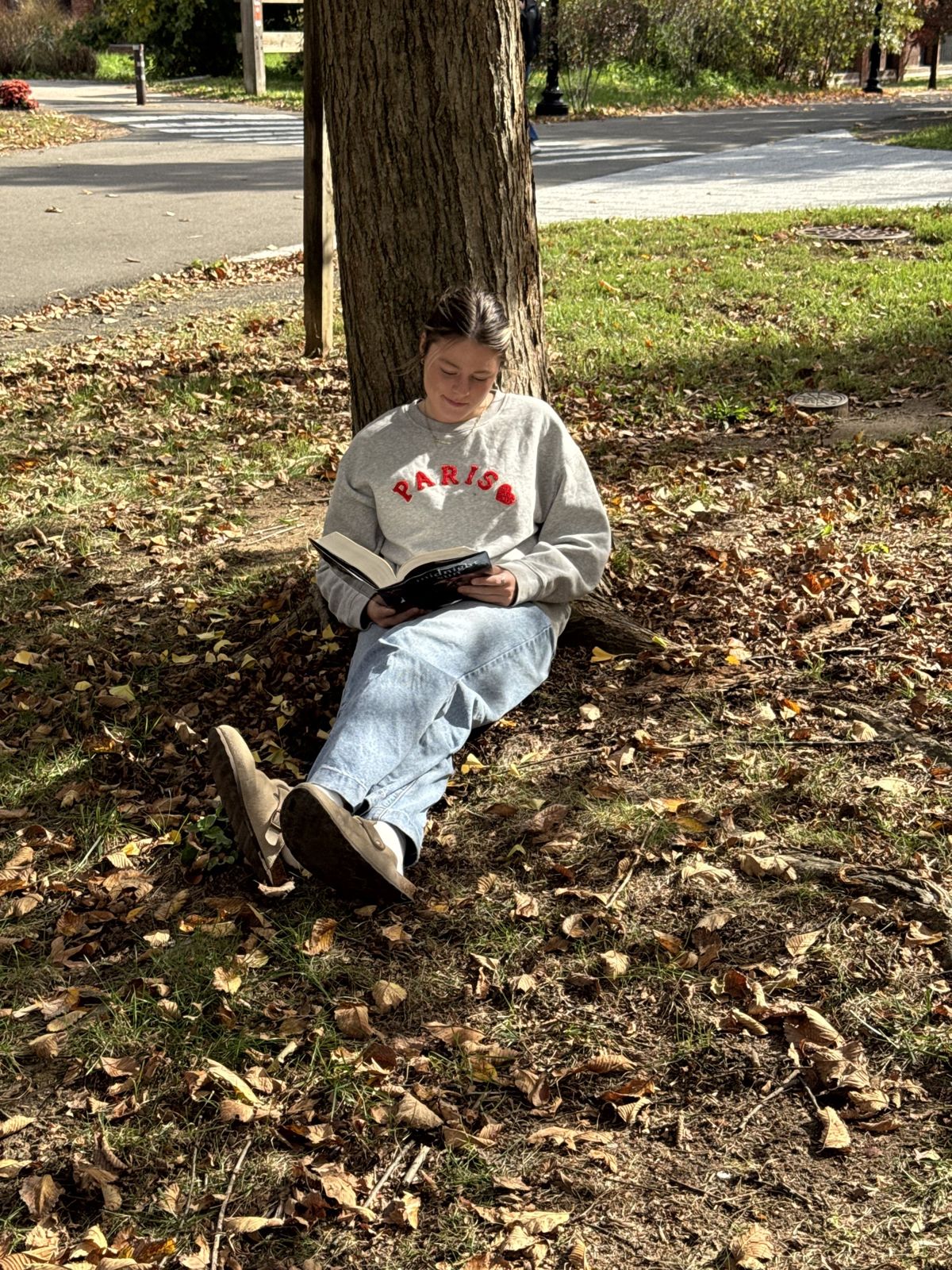 My daughter reading under a maple in a park by campus