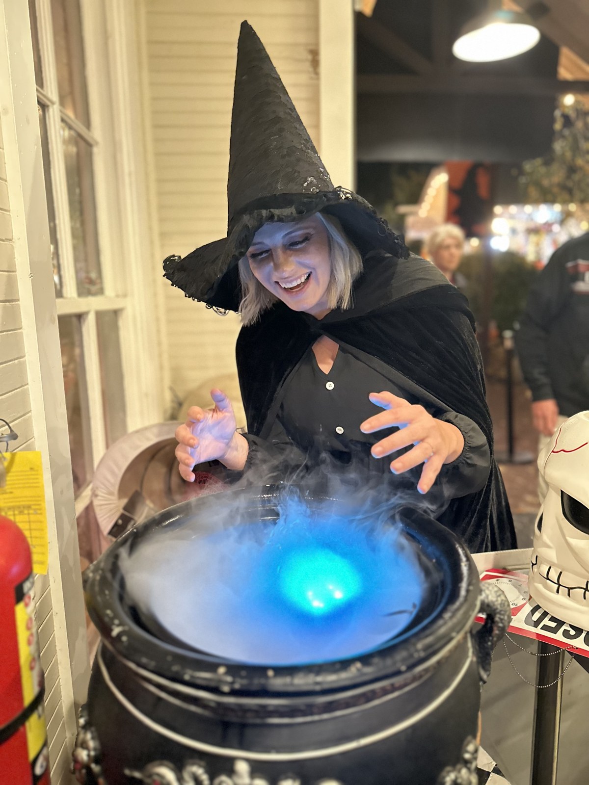 Amy in a witch hat over a glowing cauldron