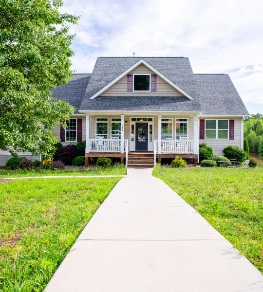 Front view of a cozy family home with a porch and green lawn.