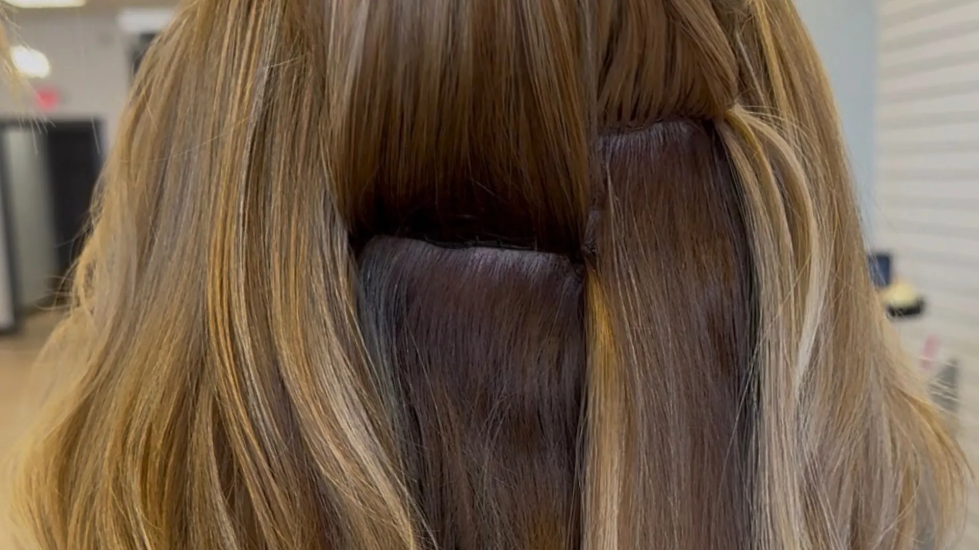 Close-up of a person sectioning and styling long, smooth, dark brown hair.