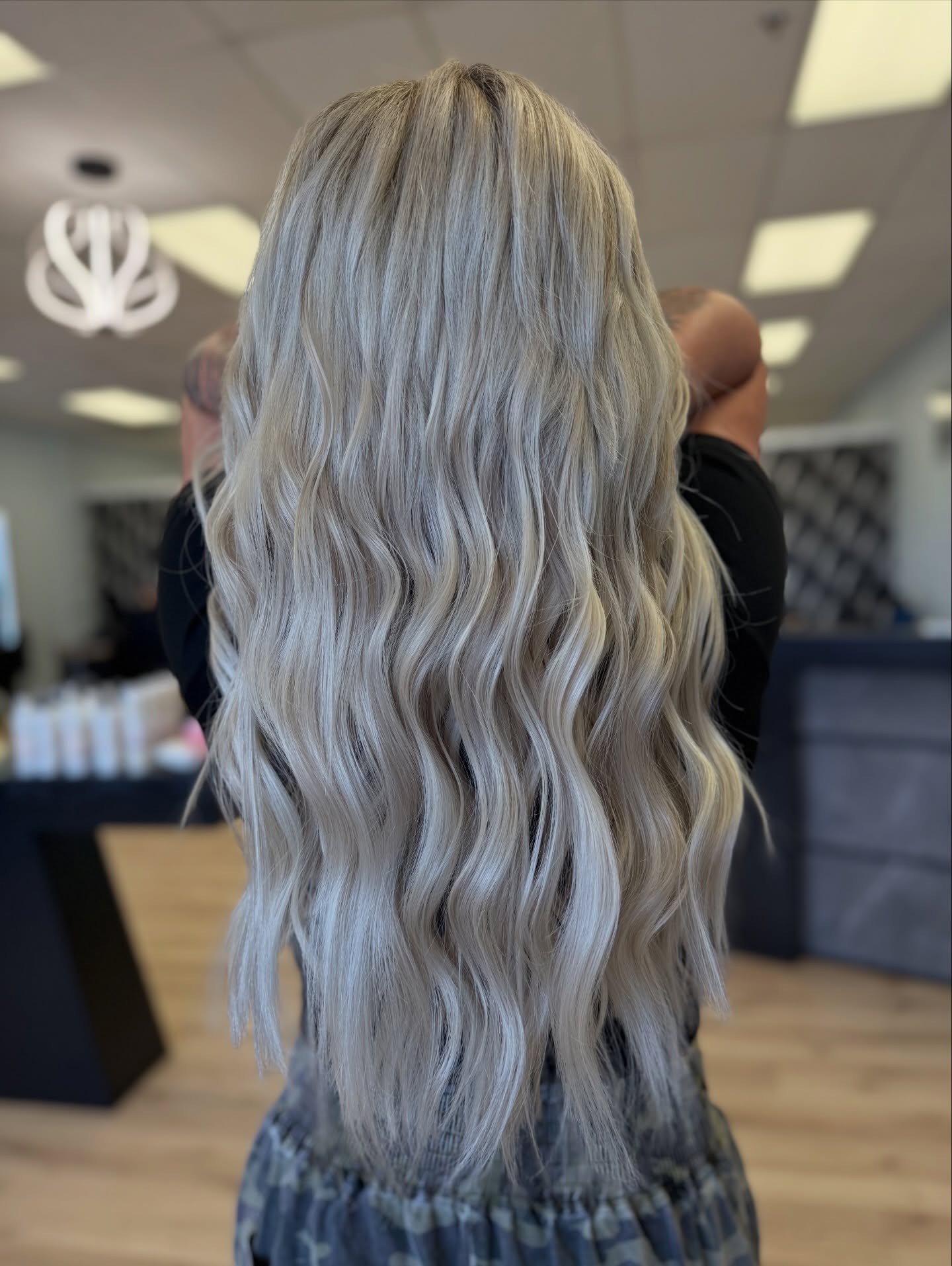 Long, wavy, platinum blonde hair viewed from the back in a salon setting.