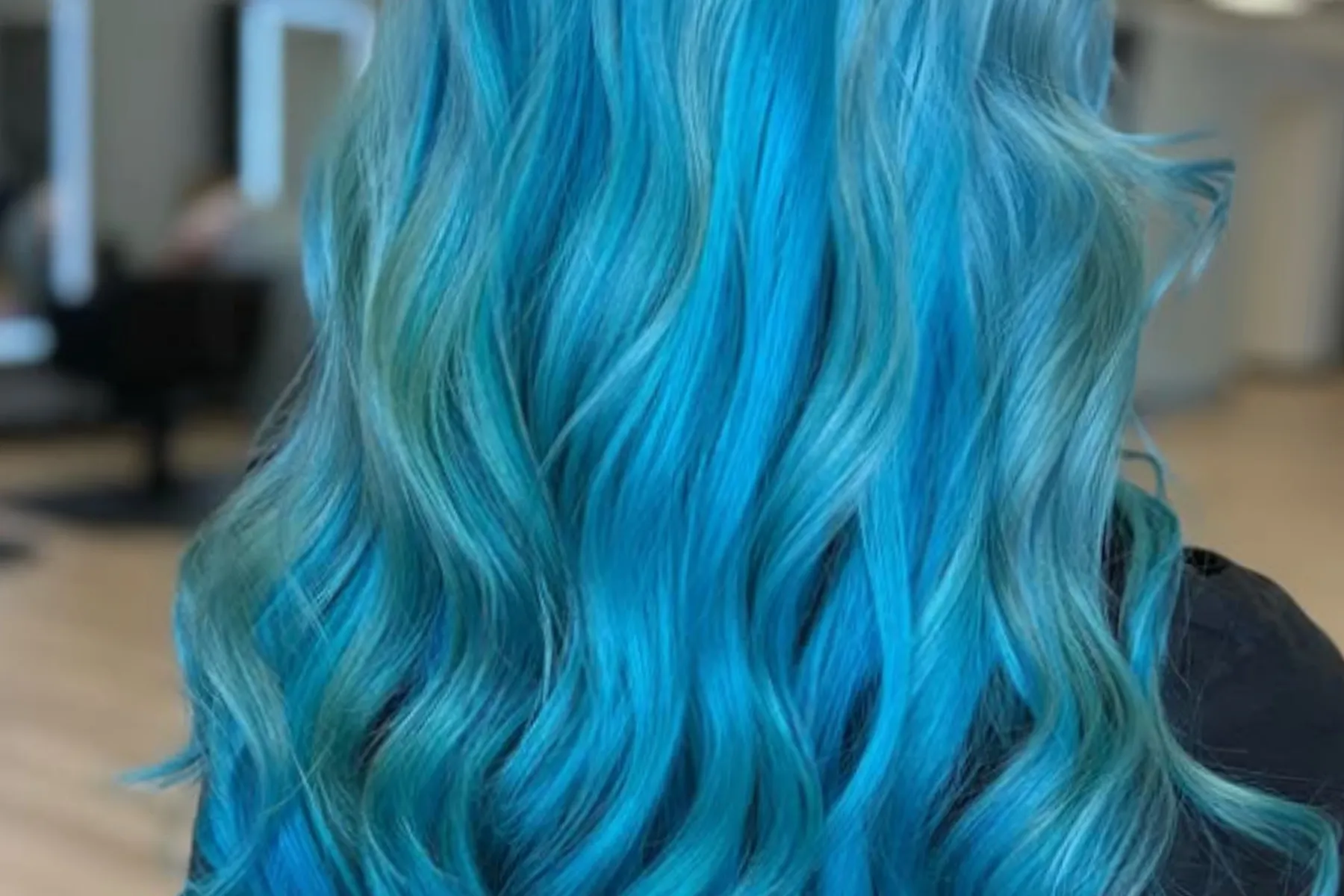 Long wavy hair dyed vibrant blue with hints of green.