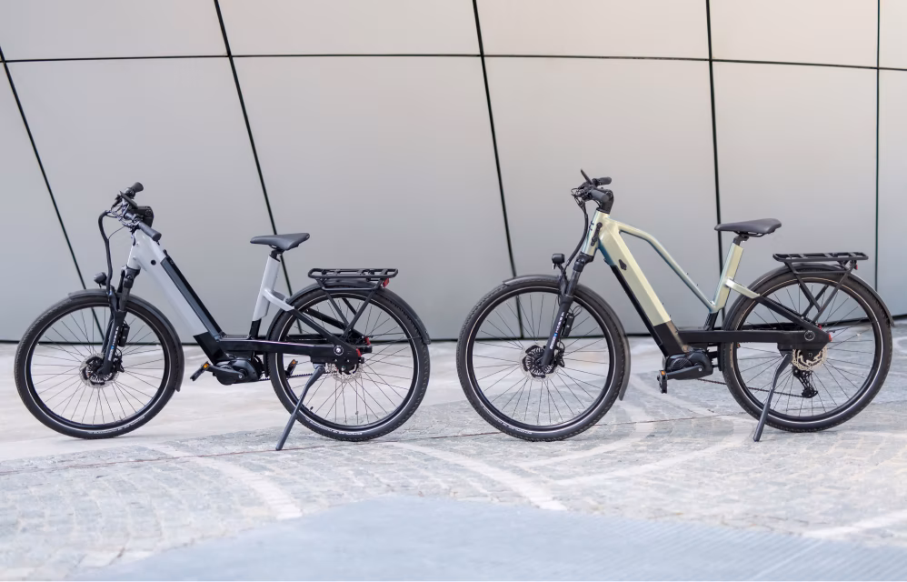 Sleek matte black electric bicycle with integrated frame and minimalist design parked against a textured concrete wall.