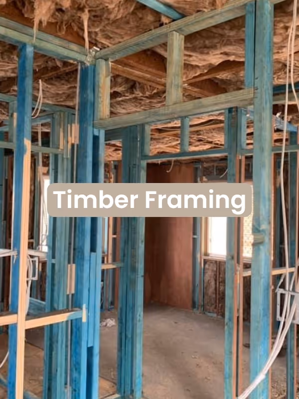 Interior of a building under construction showing blue timber framing and exposed ceiling insulation.