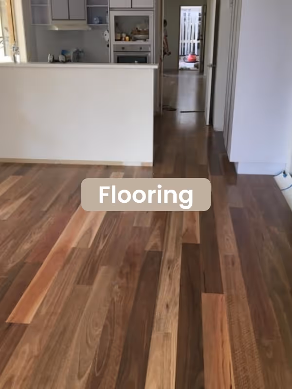 Interior view of a kitchen and hallway with polished wood flooring in varying shades of brown.