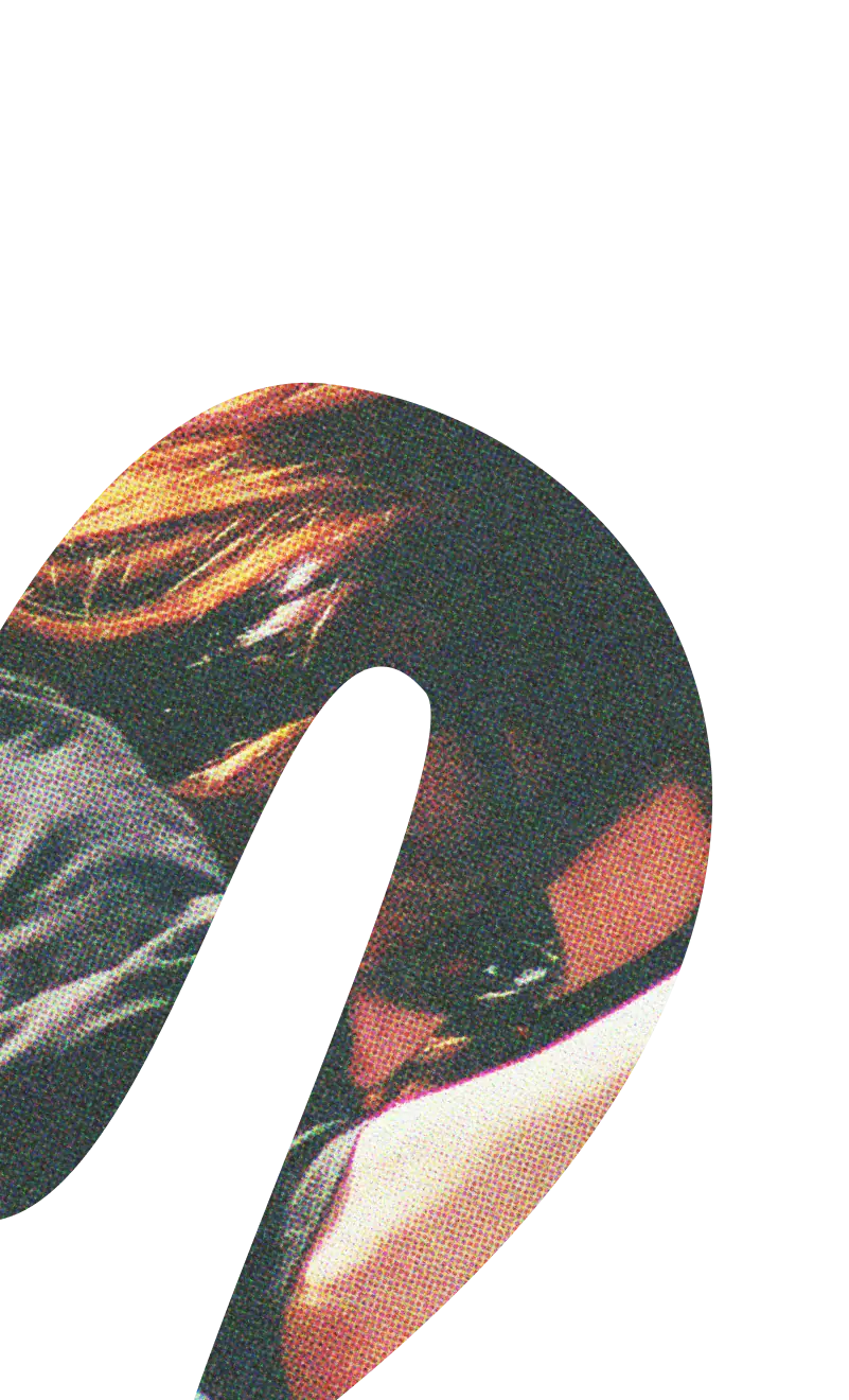 Gros plan sur une personne aux cheveux rayés de rouge et de noir, vêtue d'un vêtement noir et blanc, la tête penchée vers l'avant.