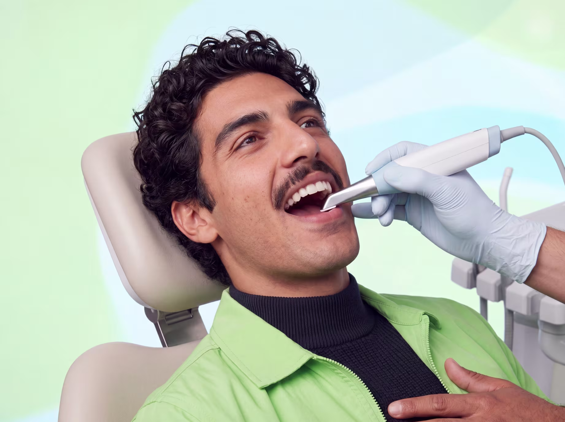 Dentist using a dental scanner inside the mouth of a smiling man in a dental chair.