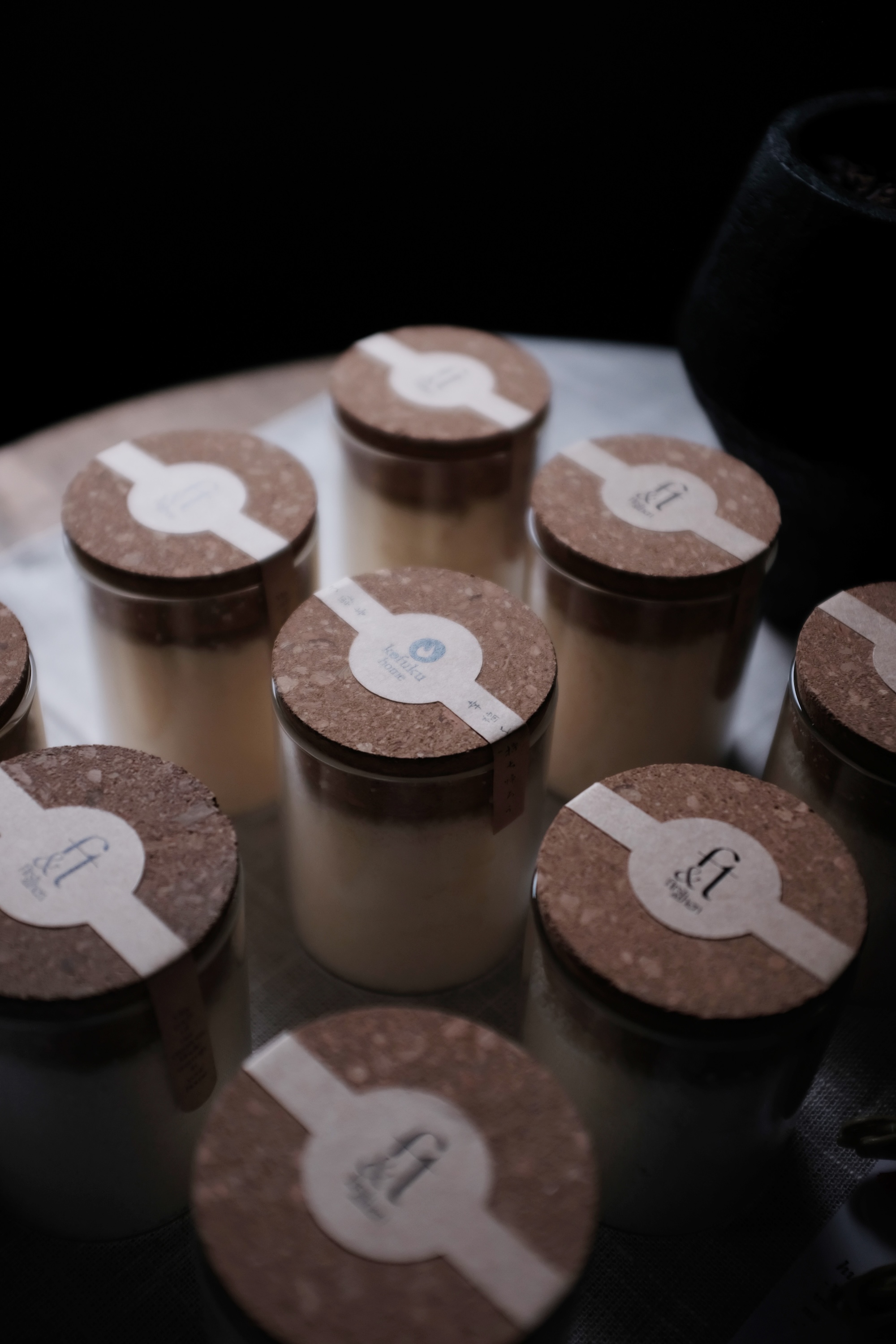 Several glass jars with cork lids arranged in a circular pattern on a table.