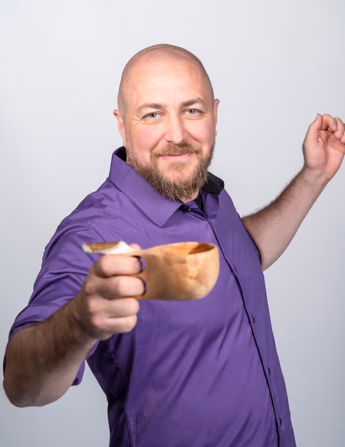 Hymyilevä Jussi, joka ojentaa puisesti kuppia kohti kameraa.