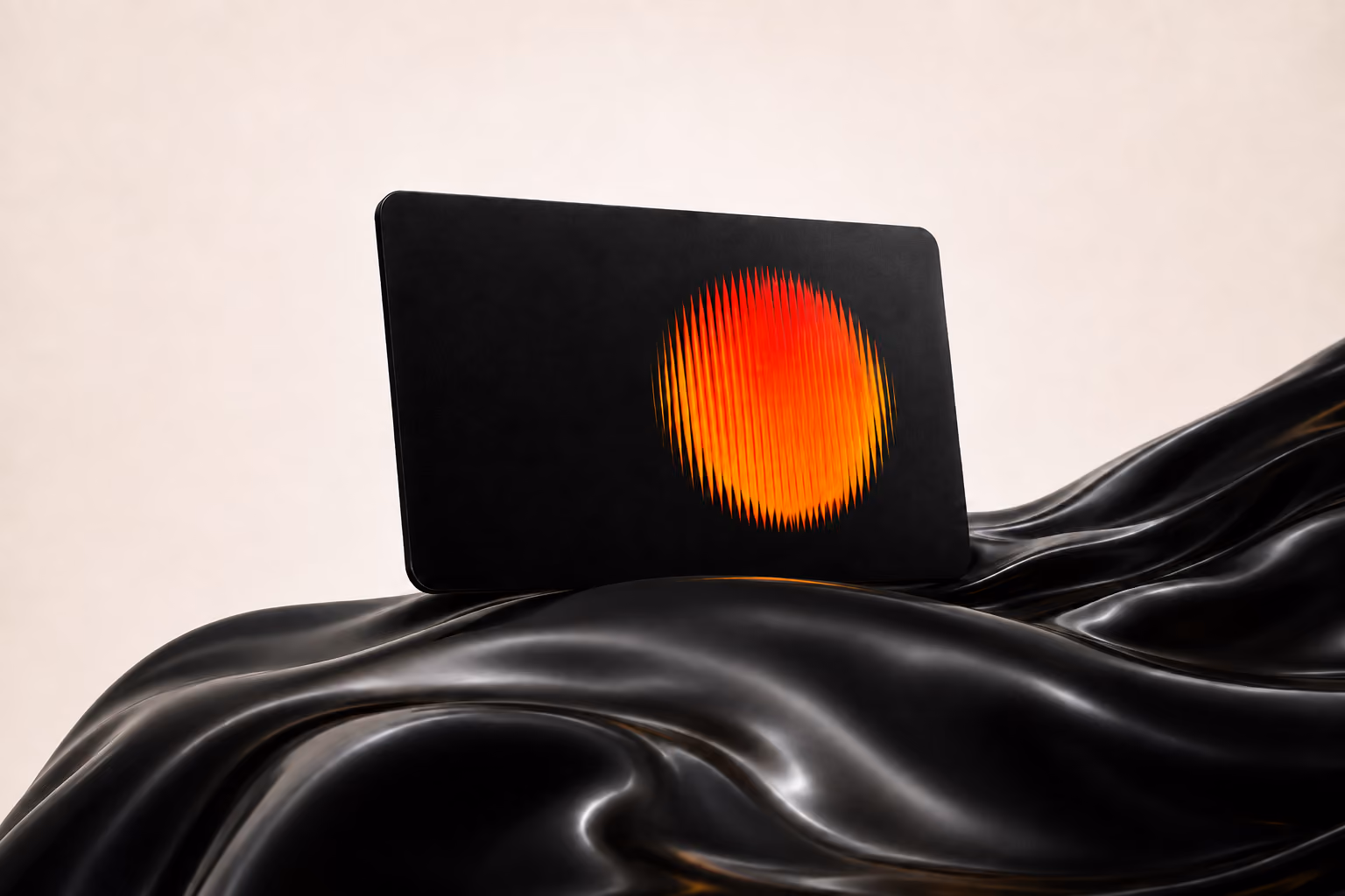 Black laptop with a vibrating red and orange circular design on the back, placed on shiny black fabric.