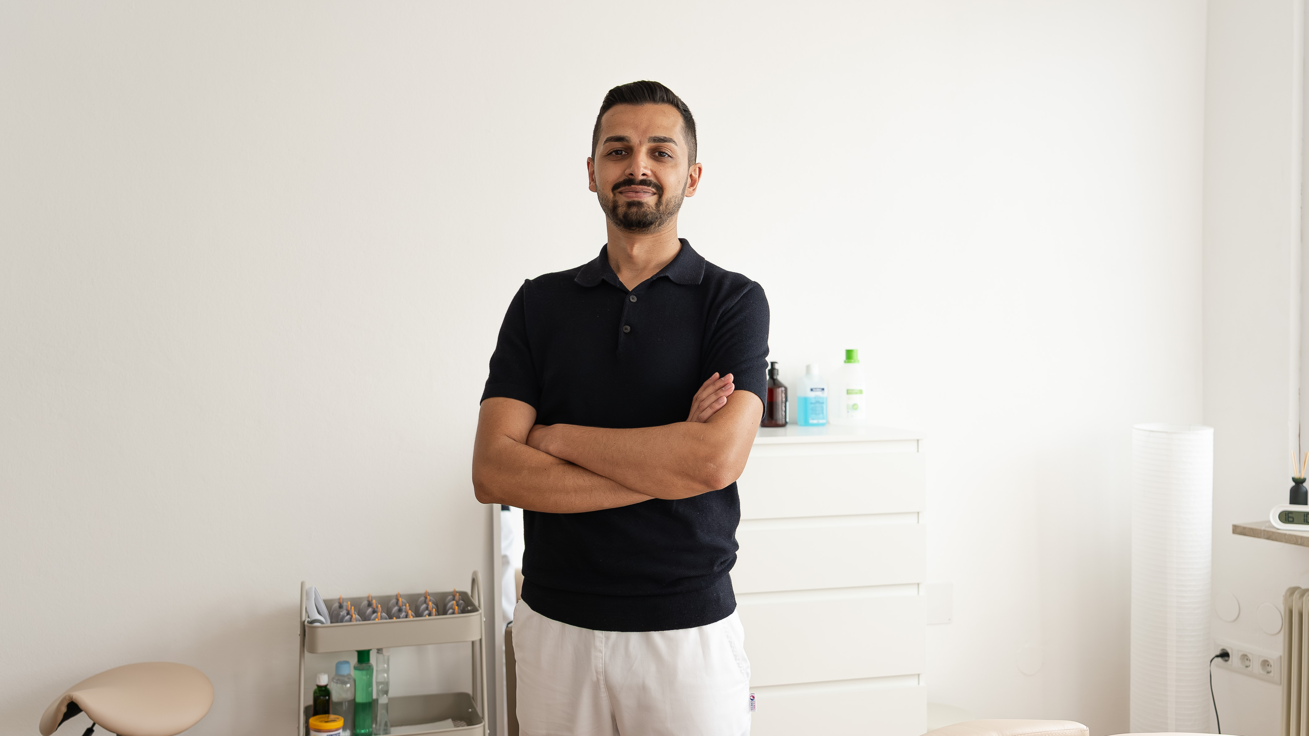 Young man in black sleeveless shirt practicing yoga indoors on a purple mat, looking sideways.
