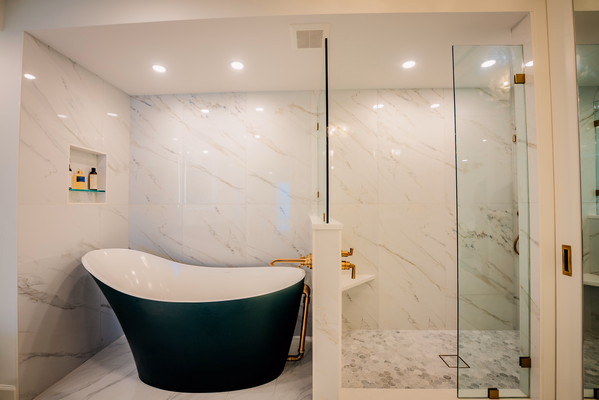 Freestanding tub beside a frameless glass shower by Grayhawk