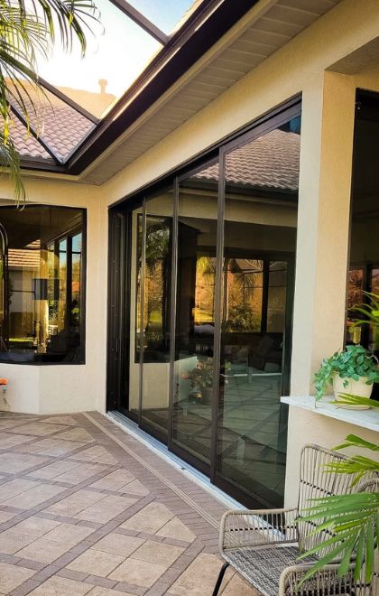Dark-framed sliding patio doors opening onto a paver lanai — patio doors
