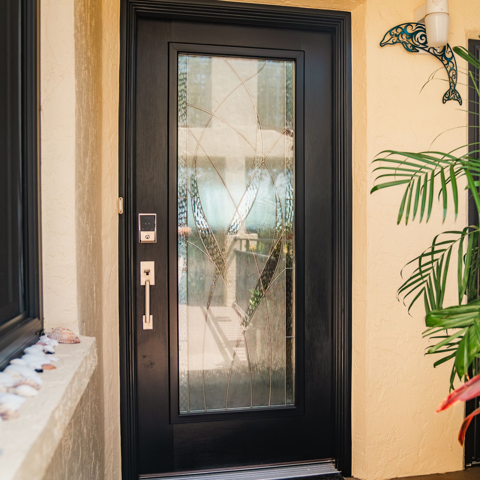 Black entry door with etched decorative glass on a stucco home