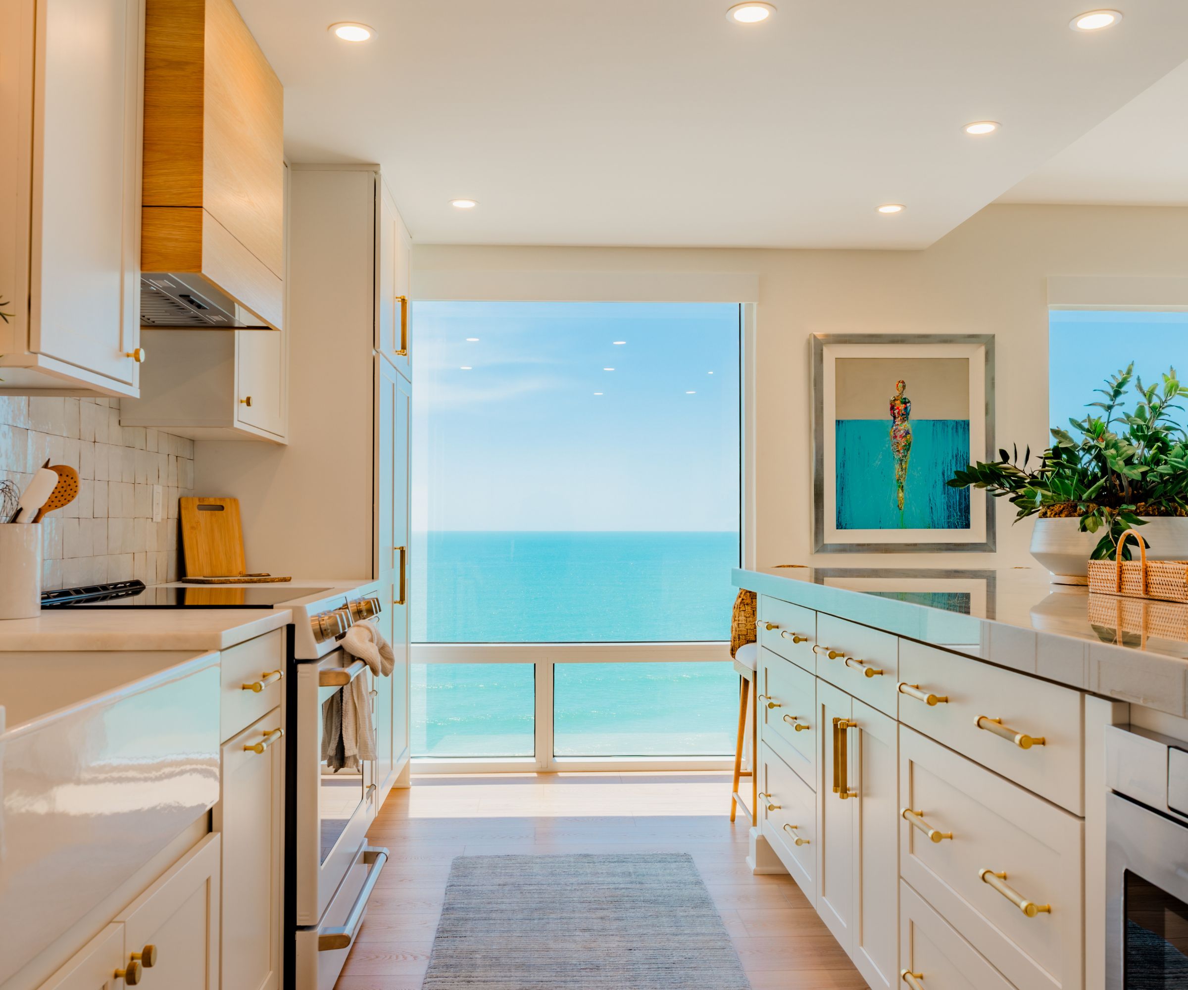 Galley kitchen with white cabinets and a floor-to-ceiling window over the Gulf
