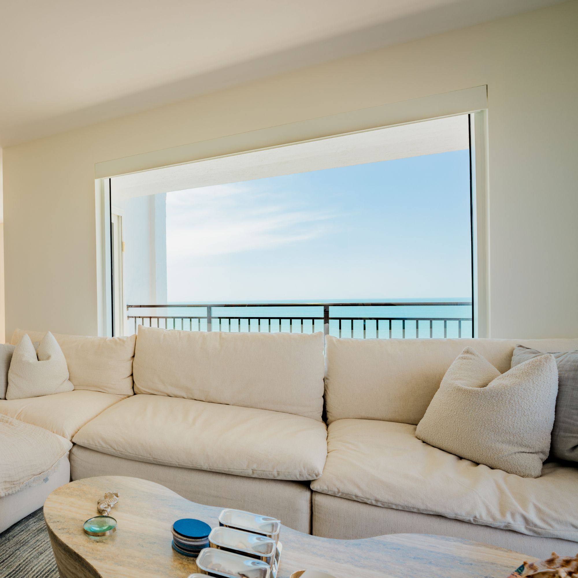 Living room sofa beneath a large impact window overlooking a balcony and water
