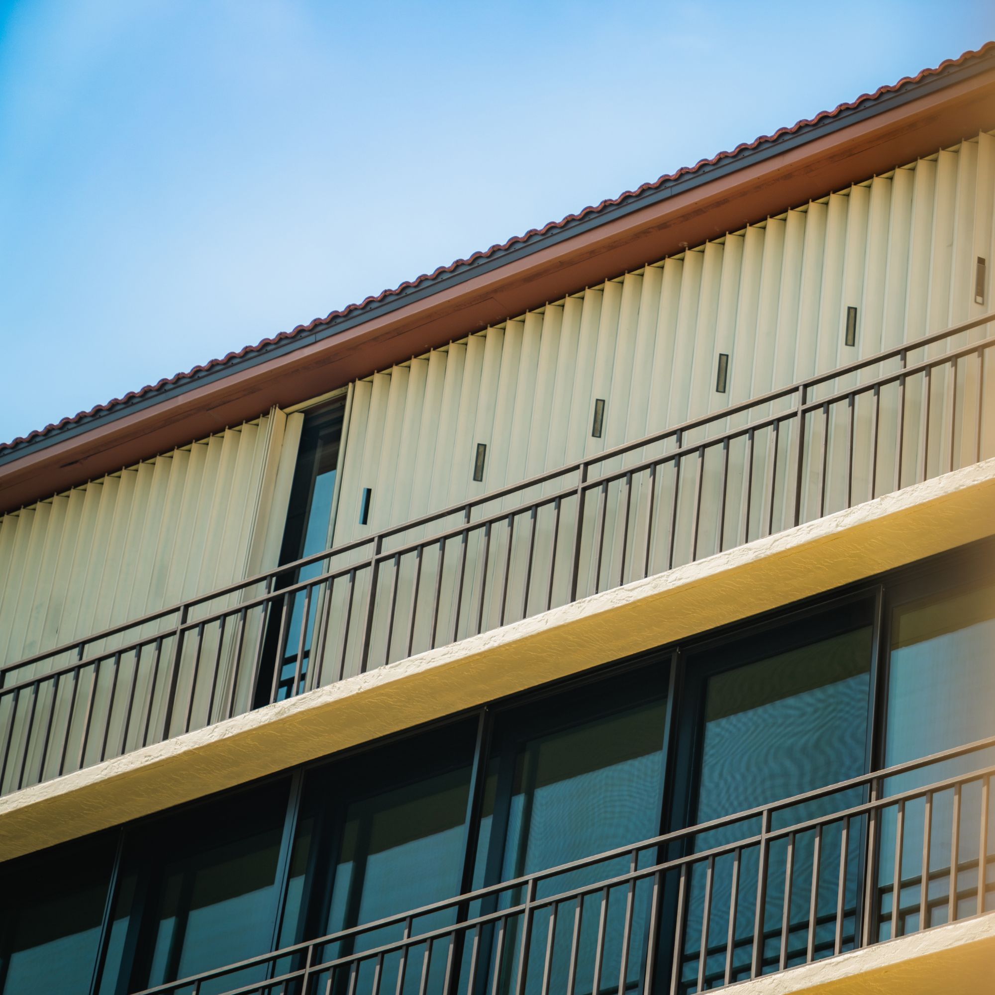 Roll-down hurricane shutters closed along a condo building's upper balcony