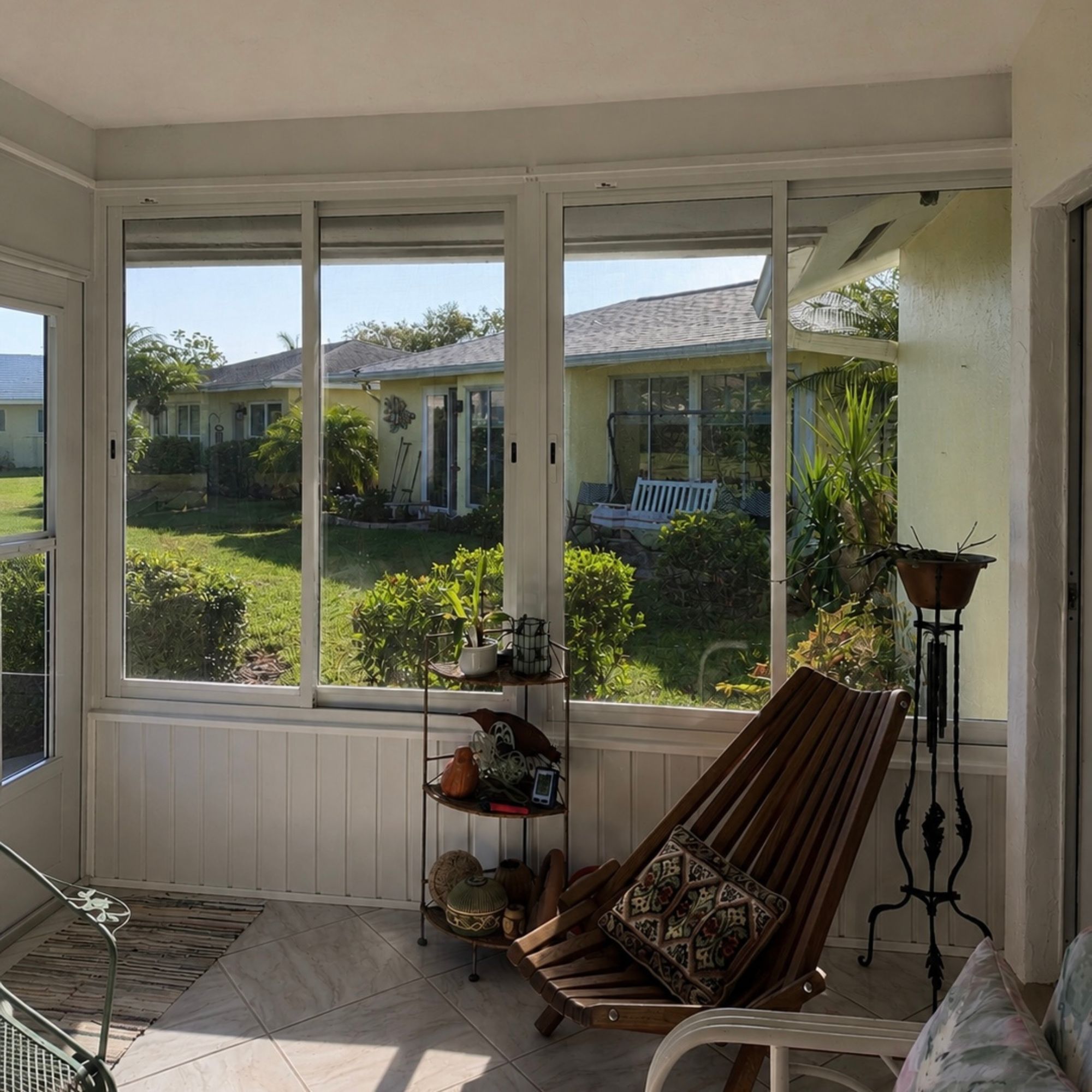Enclosed lanai with sliding windows and beadboard wainscot overlooking a lawn