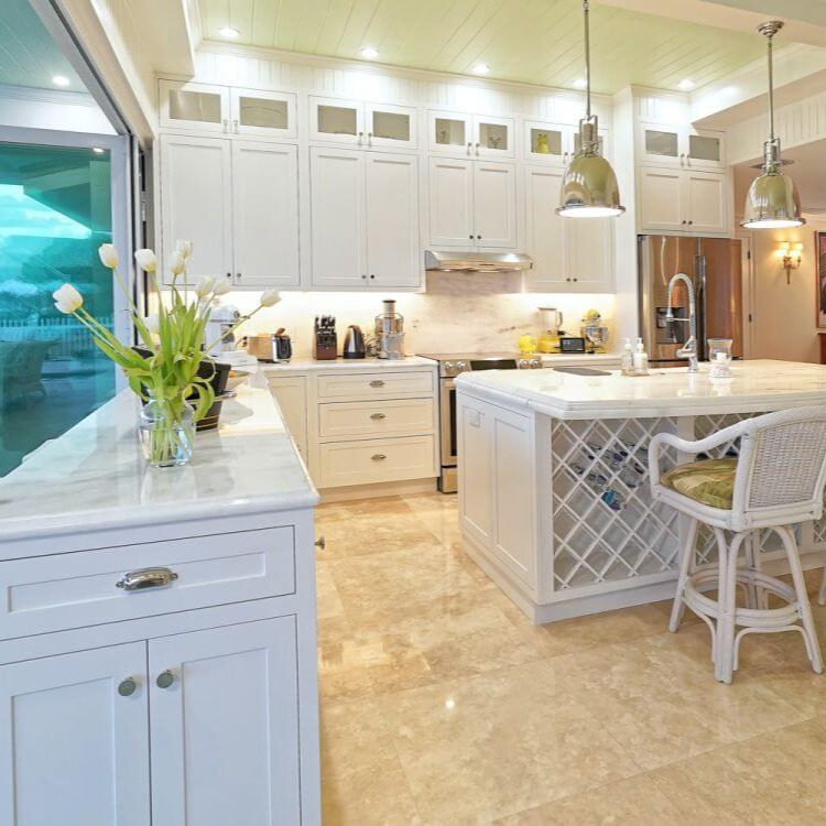 White kitchen with marble counters, pendant lights and a wine-rack island