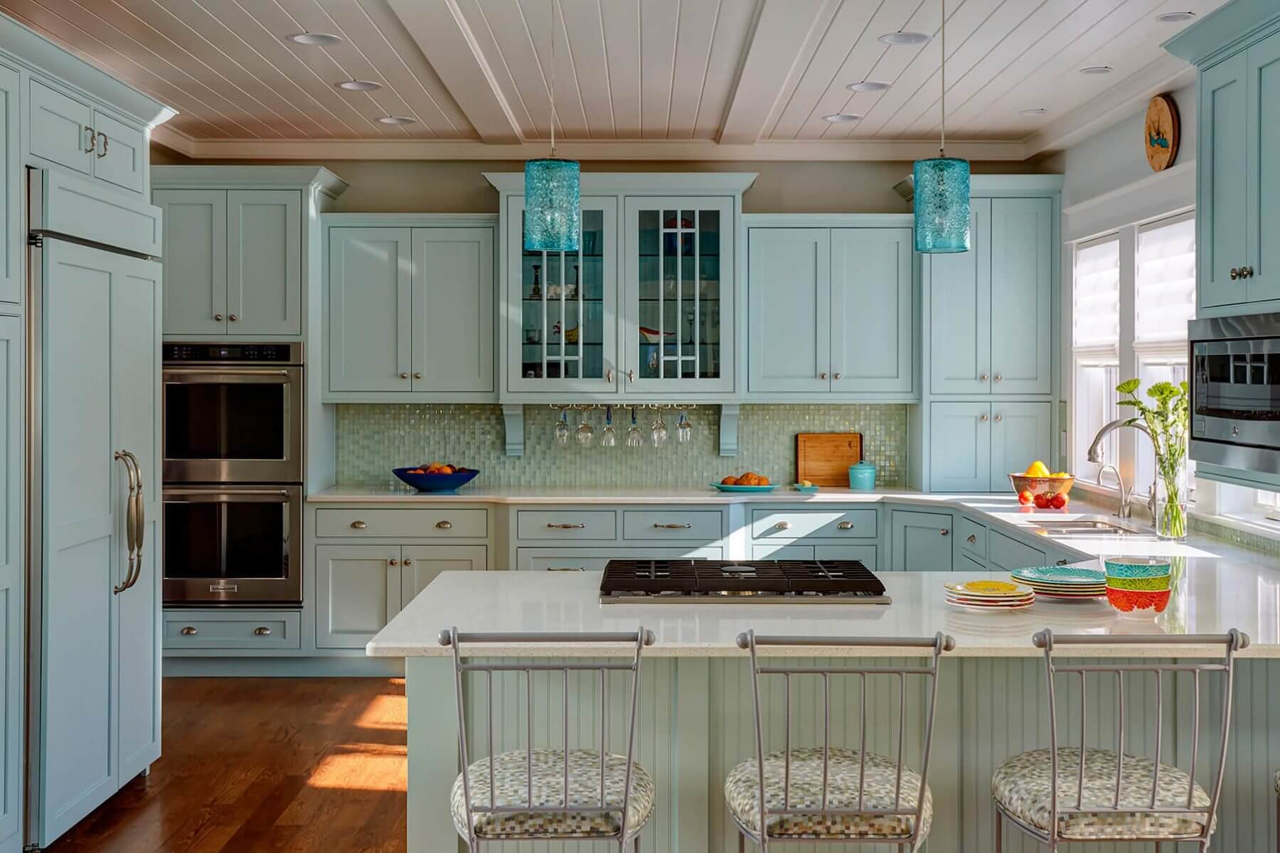 Coastal kitchen with sea-glass green cabinets, a plank ceiling and island seating