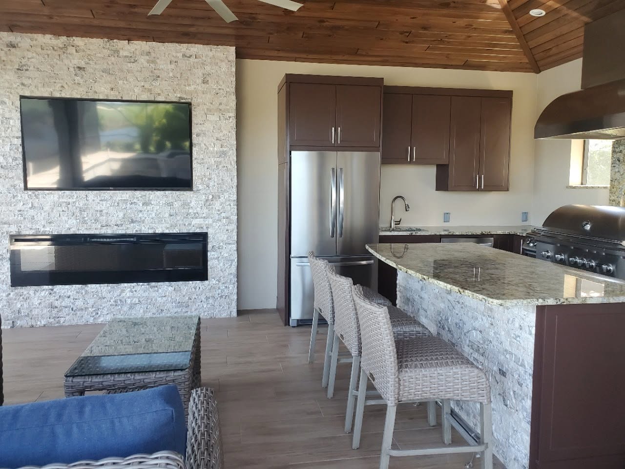 Open living and kitchen space with a stone fireplace wall and granite bar seating