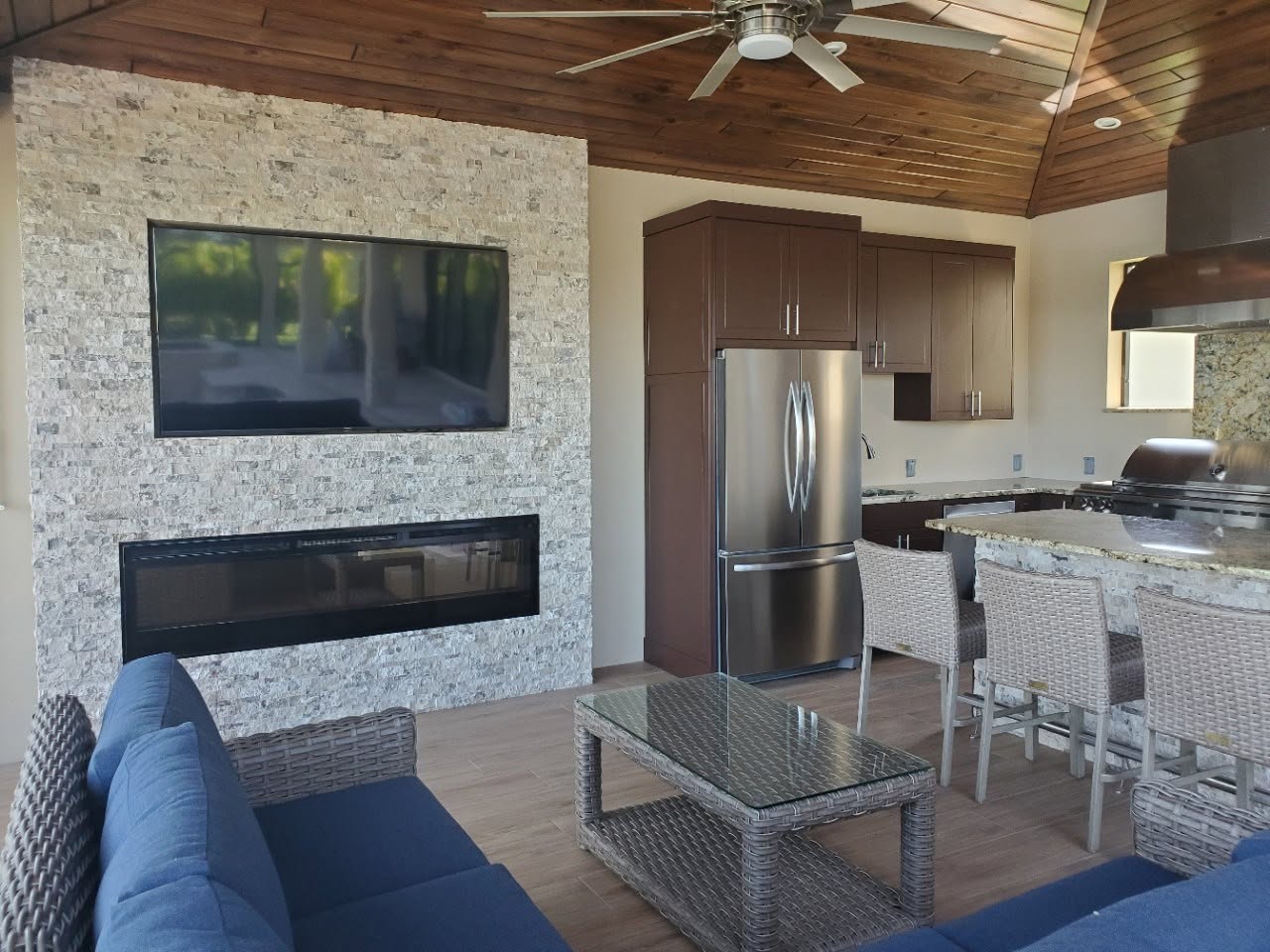 Living area with a linear fireplace, stacked stone wall and wood plank ceiling
