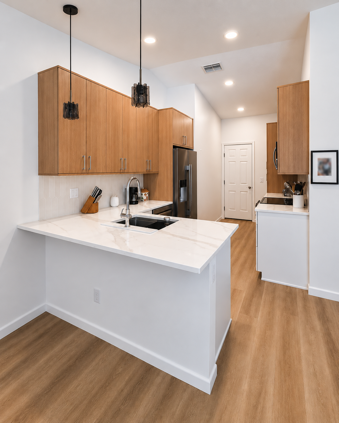 Open kitchen with a quartz peninsula, oak cabinets and pendant lighting