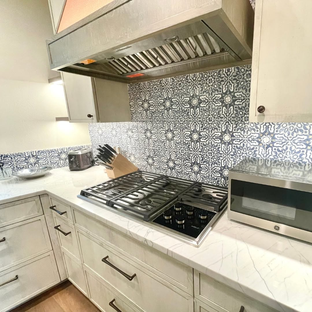 Kitchen with a stainless range hood, patterned tile backsplash and quartz counters