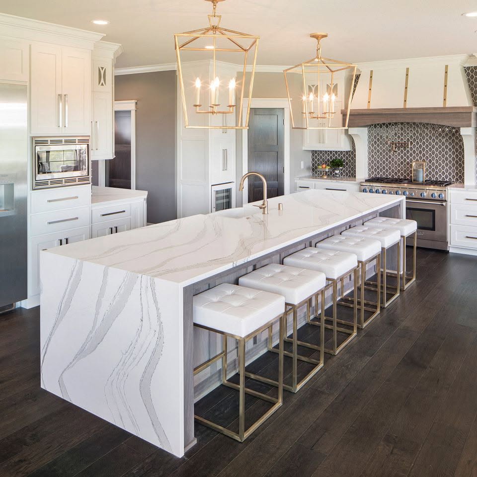 Remodeled kitchen with a waterfall quartz island, brass pendants and bar stools
