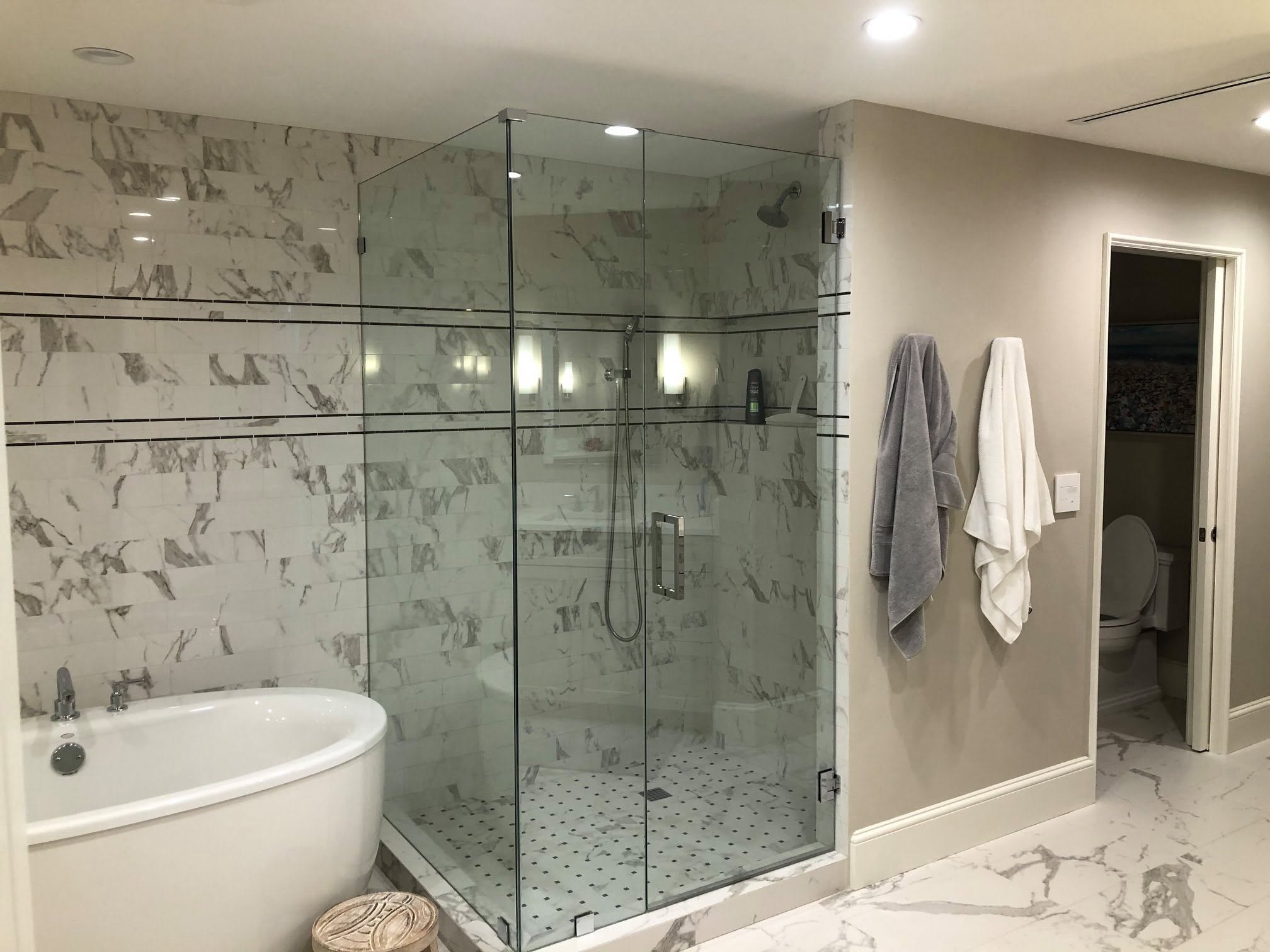 Remodeled bathroom with a freestanding tub and marble-tiled glass shower