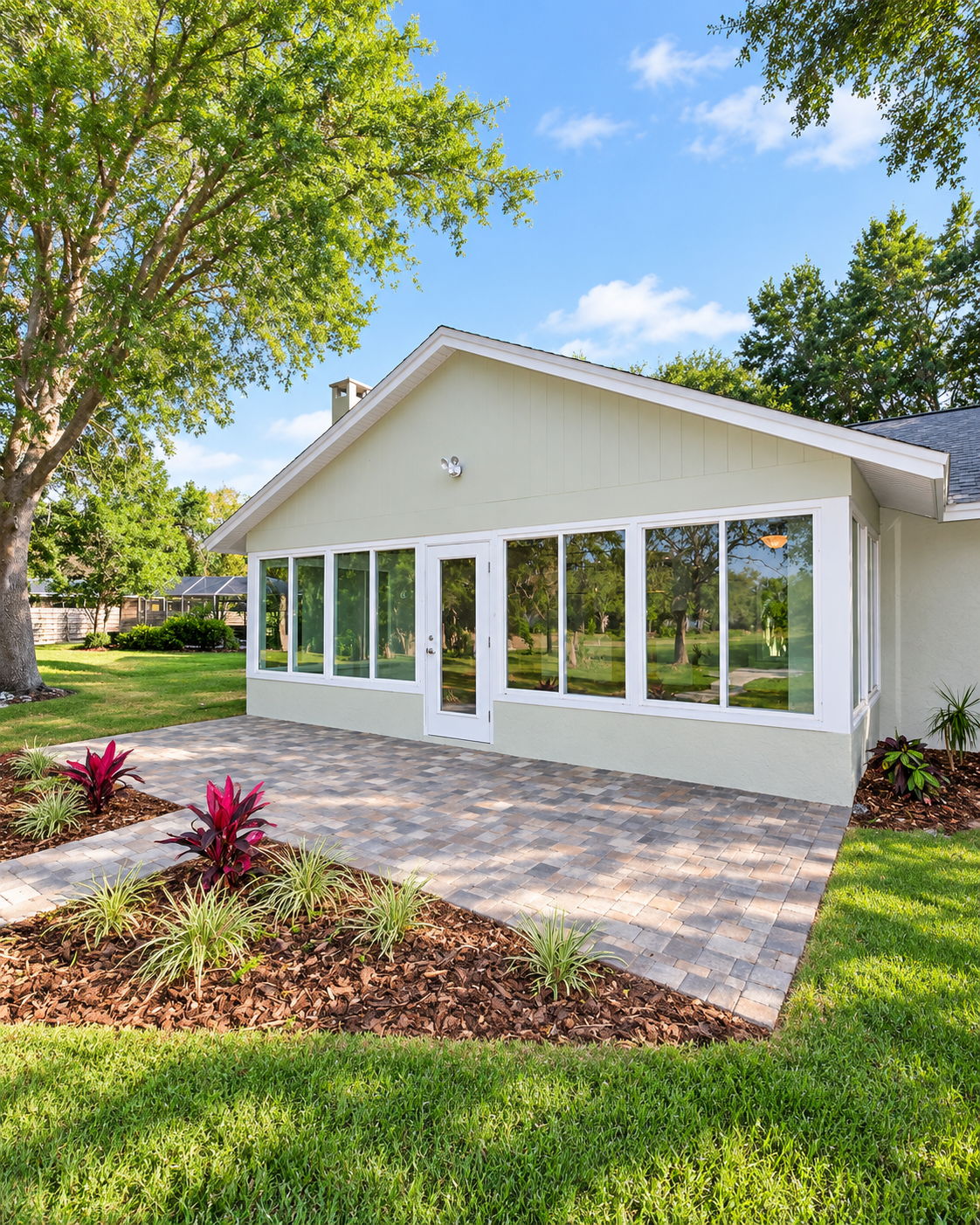 Lanai enclosure addition with wraparound windows and a paver patio