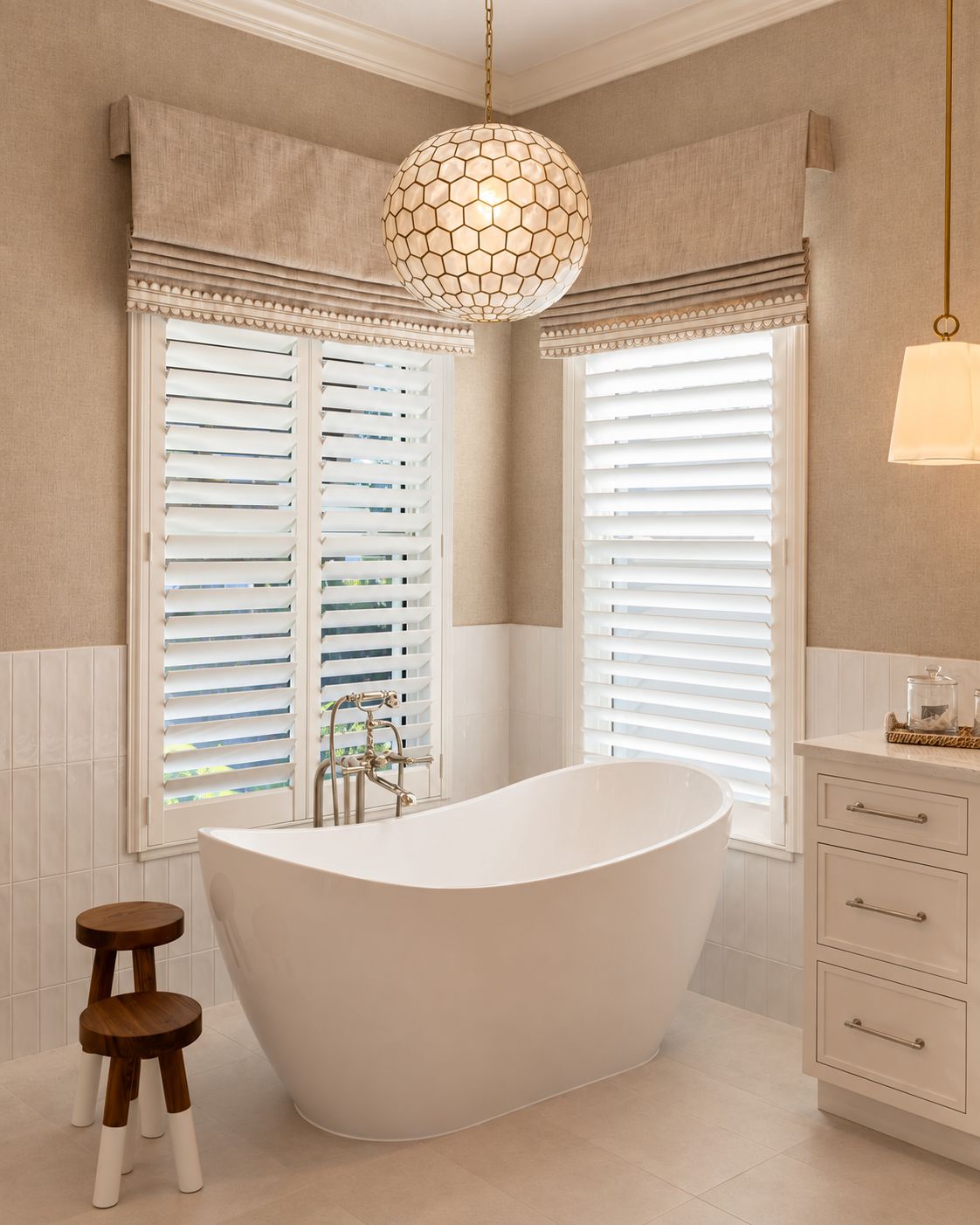 Freestanding soaking tub between shuttered windows under a woven globe pendant