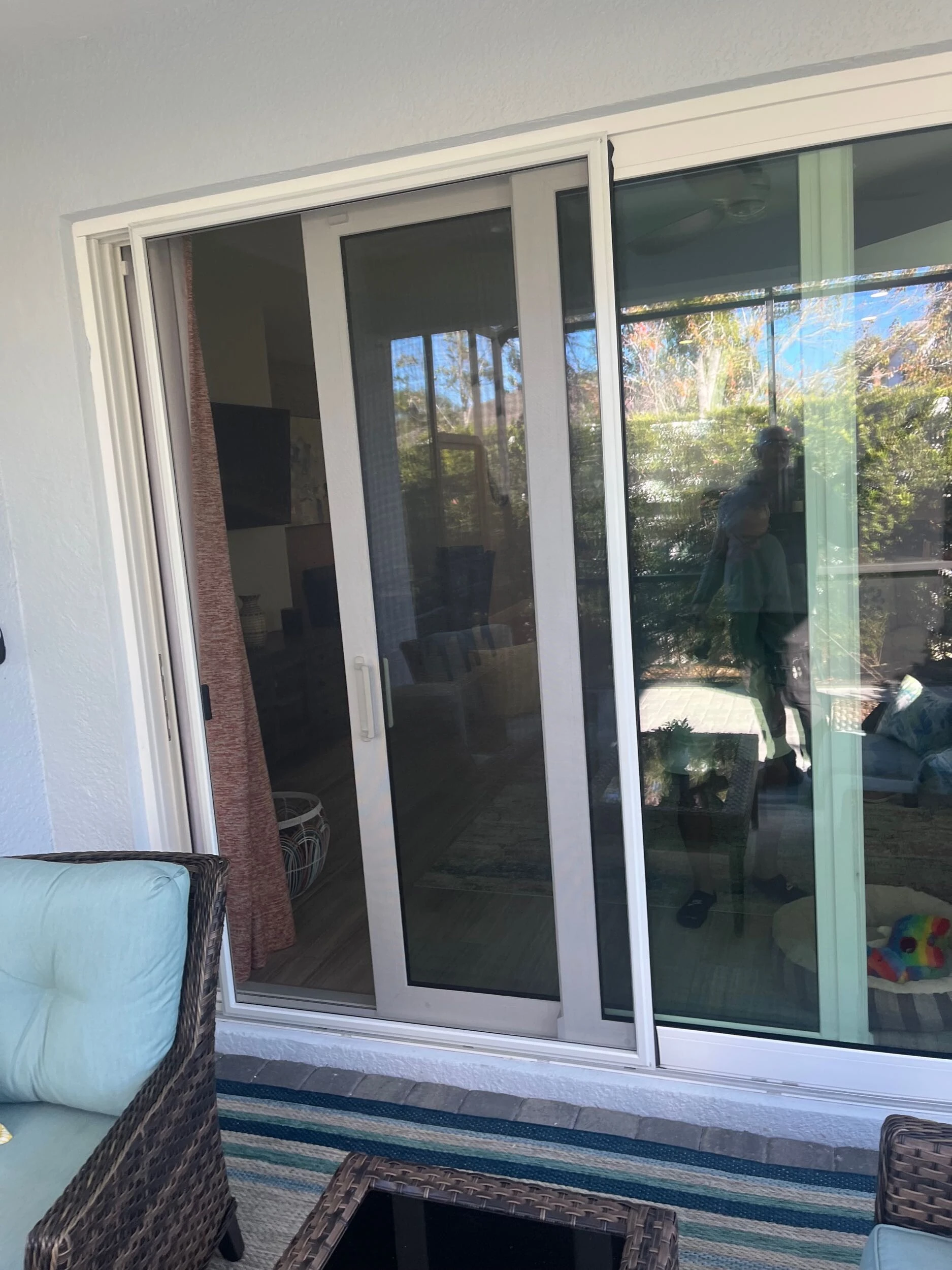 Sliding glass door open to a screened lanai with patio furniture