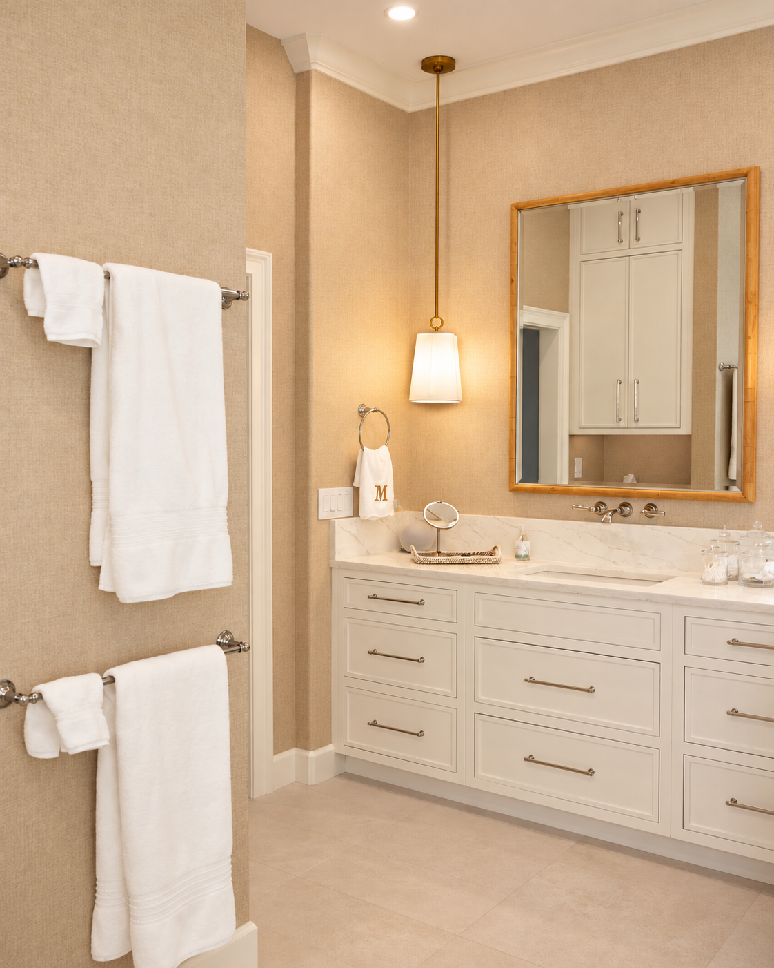 Bathroom with a long white vanity, gold-framed mirror and towel bars