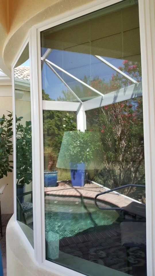 Large picture window reflecting a screened pool enclosure