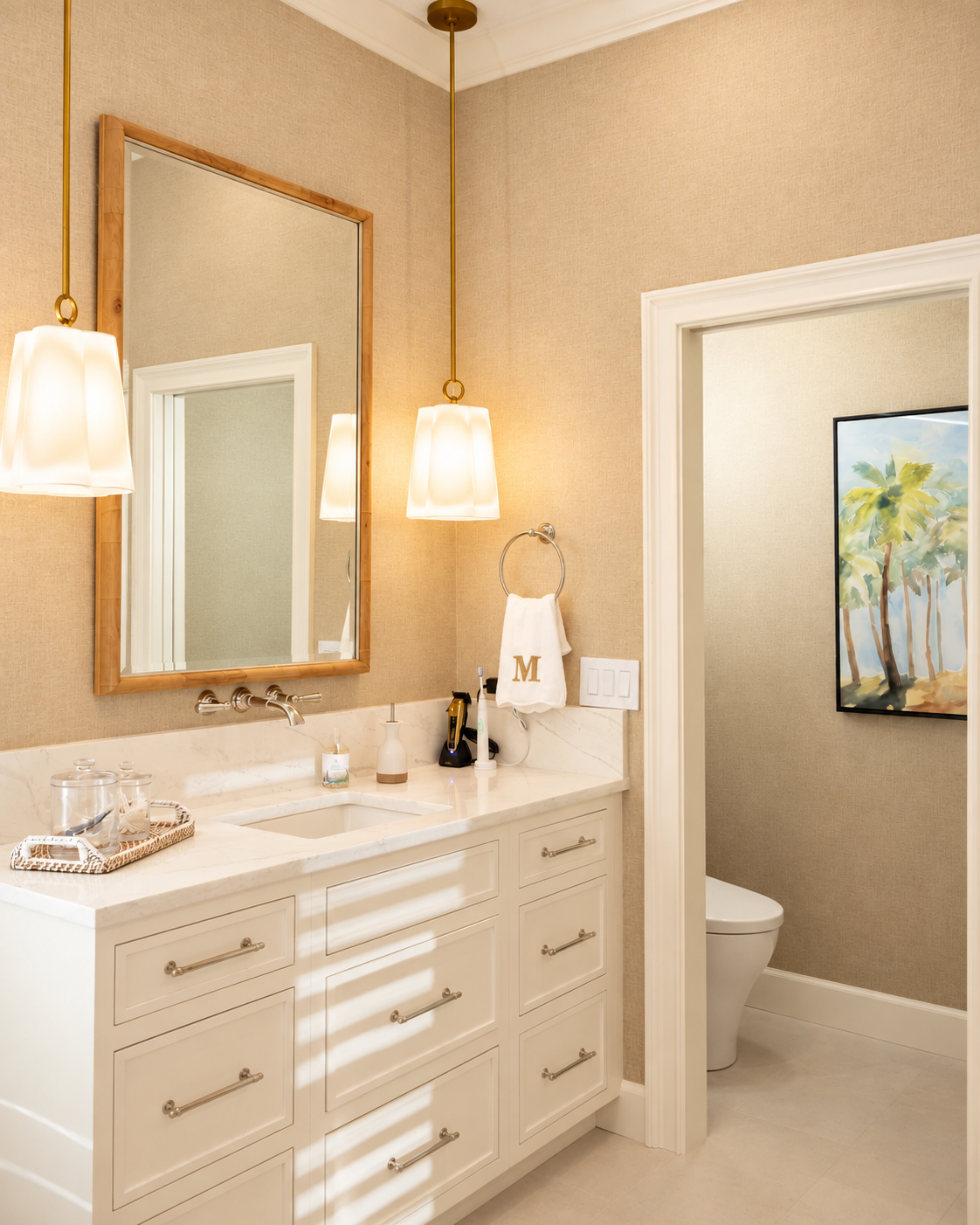 Bathroom vanity with a gold-framed mirror, glass pendants and adjoining water closet