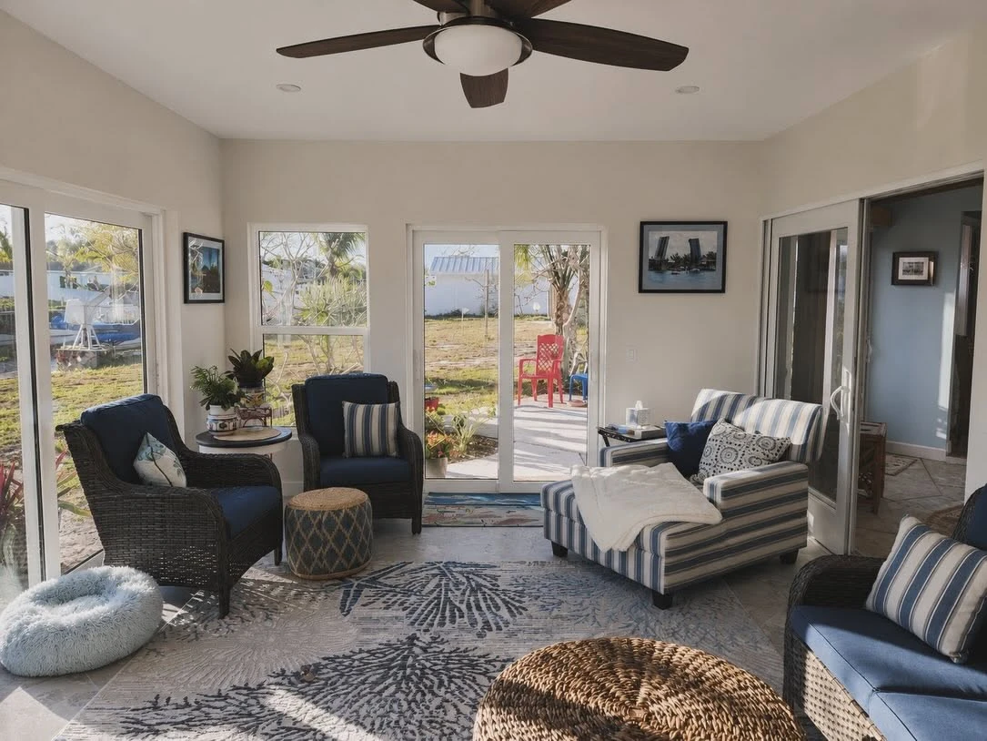 Sunroom with wraparound windows, sliding door and coastal furnishings