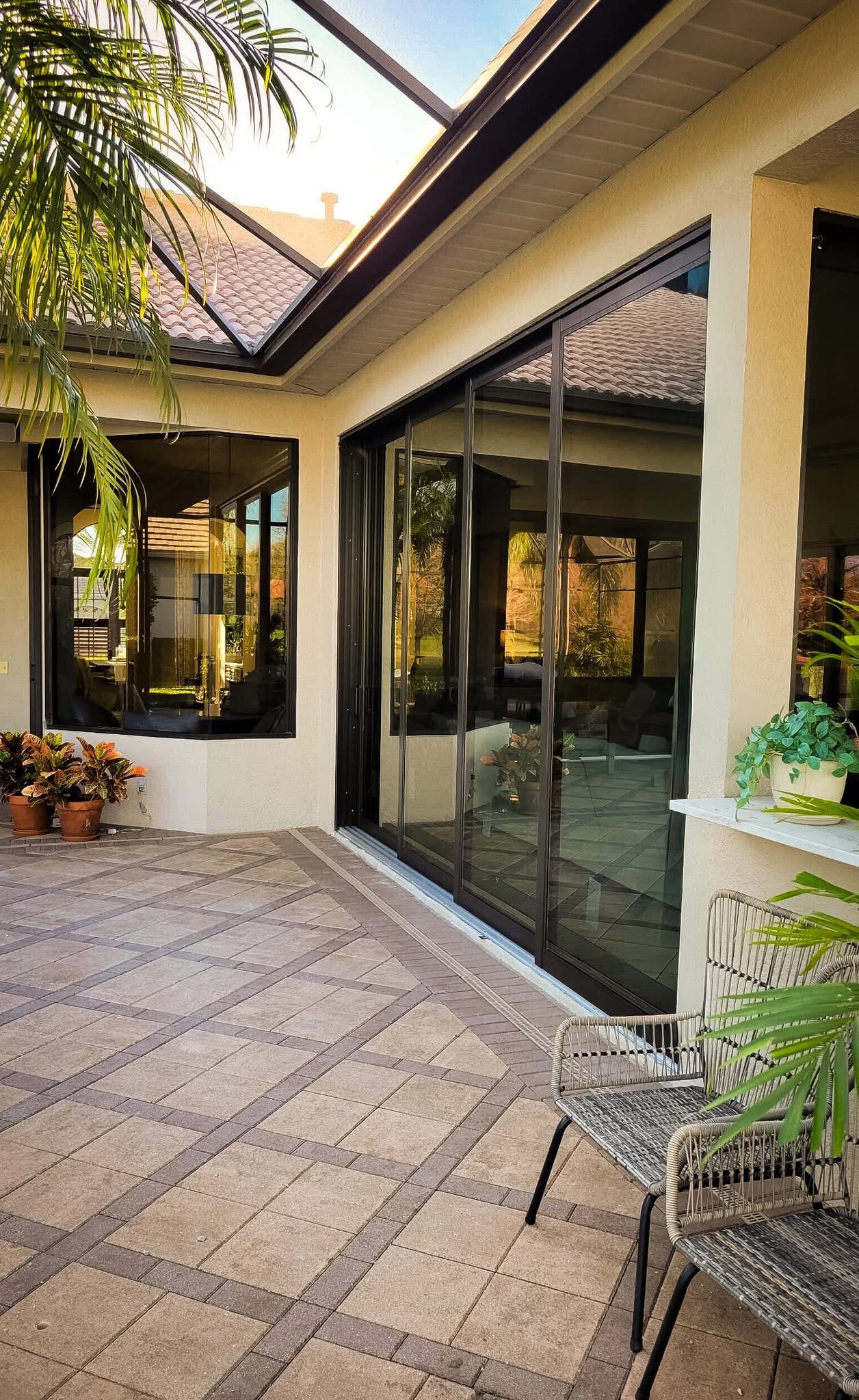 Dark-framed sliding glass doors along a covered paver lanai