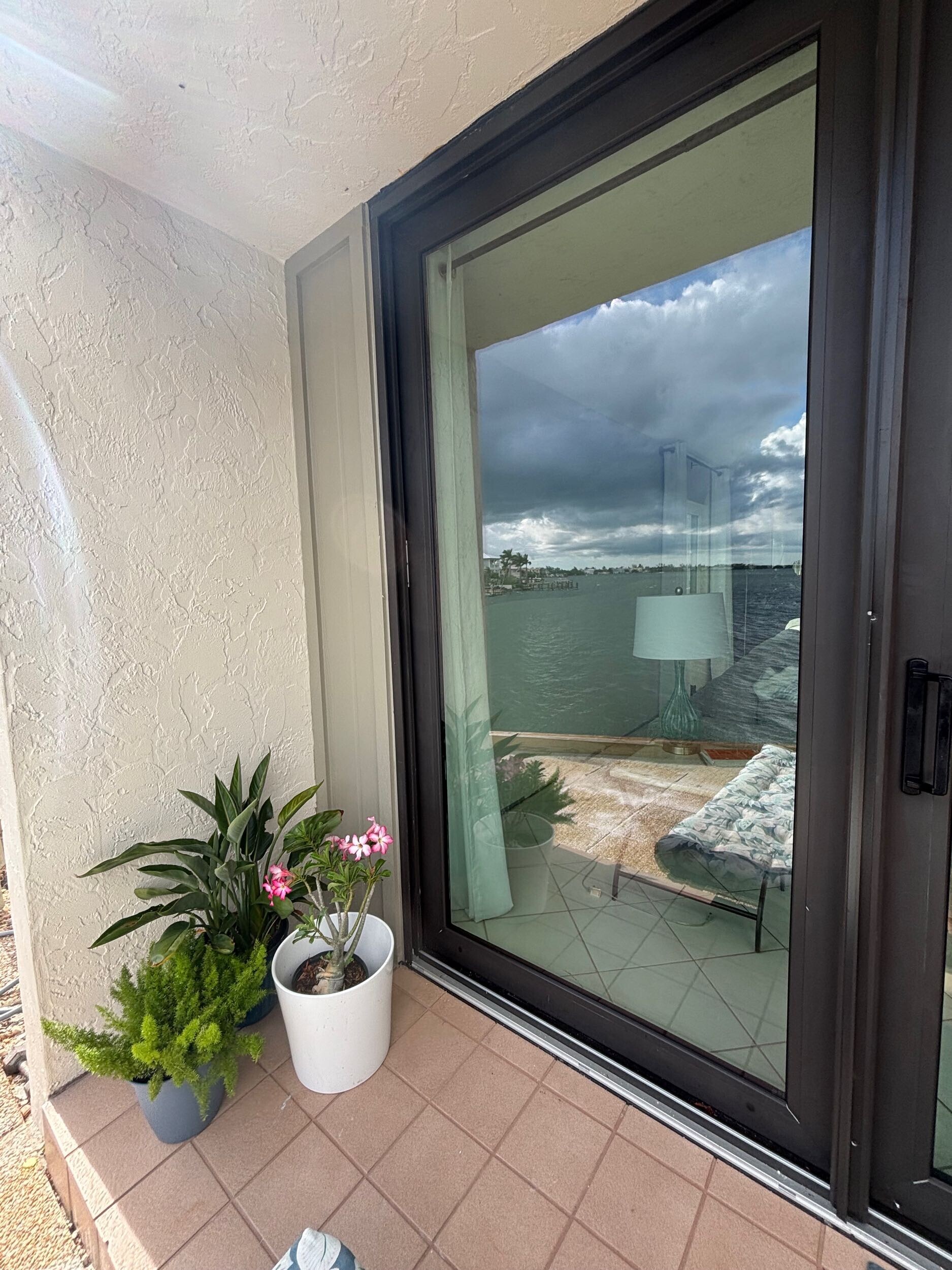 Bronze-framed sliding glass door opening to a waterfront patio