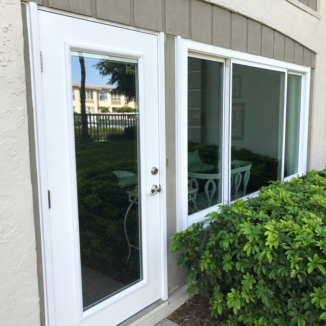 White patio door and window unit opening onto a landscaped backyard