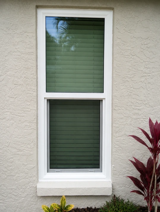 White vinyl single hung replacement window on a stucco wall